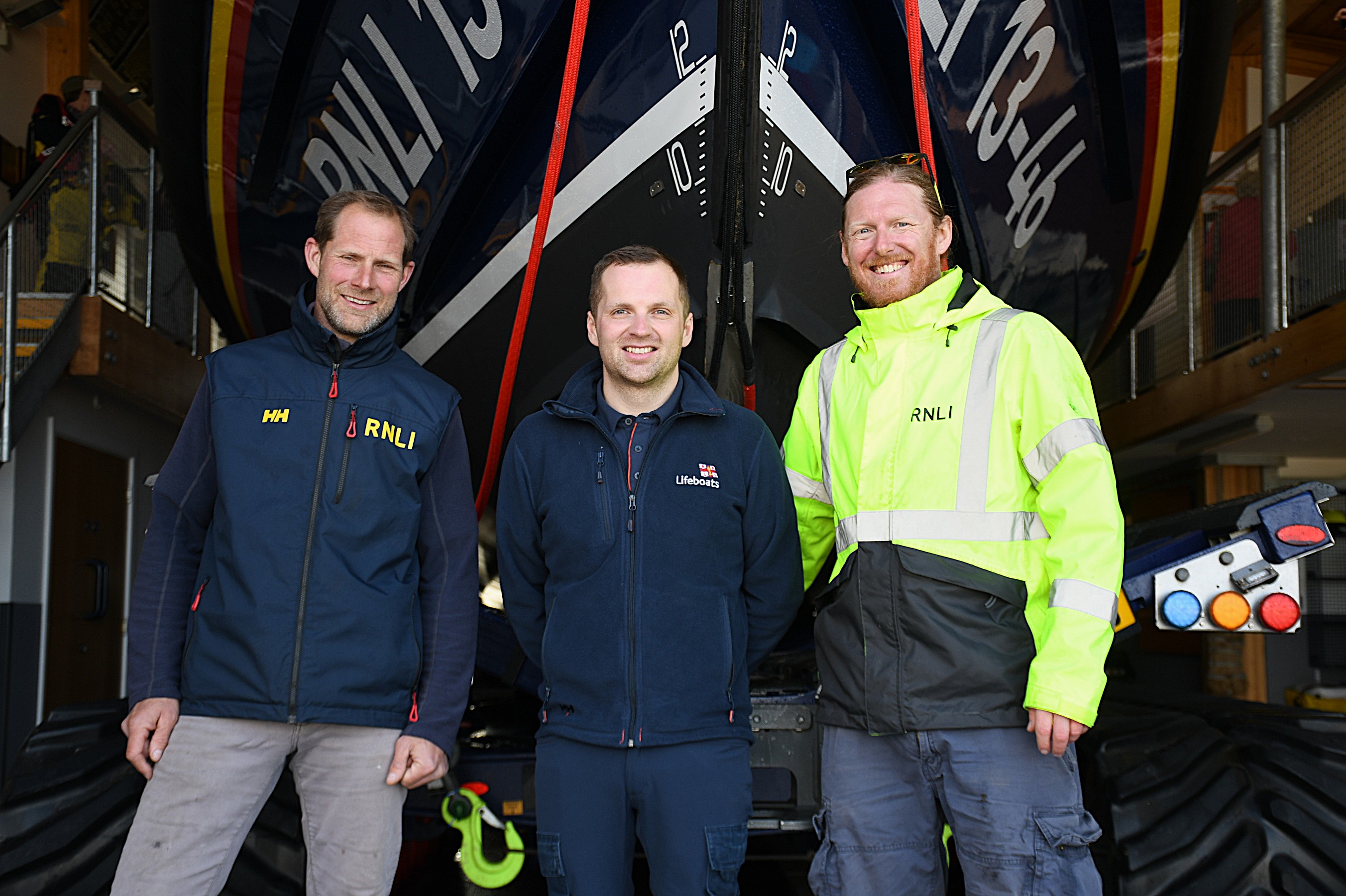 Three RNLI personnel in front of Wells RNLIs Shannon class lifeboat 