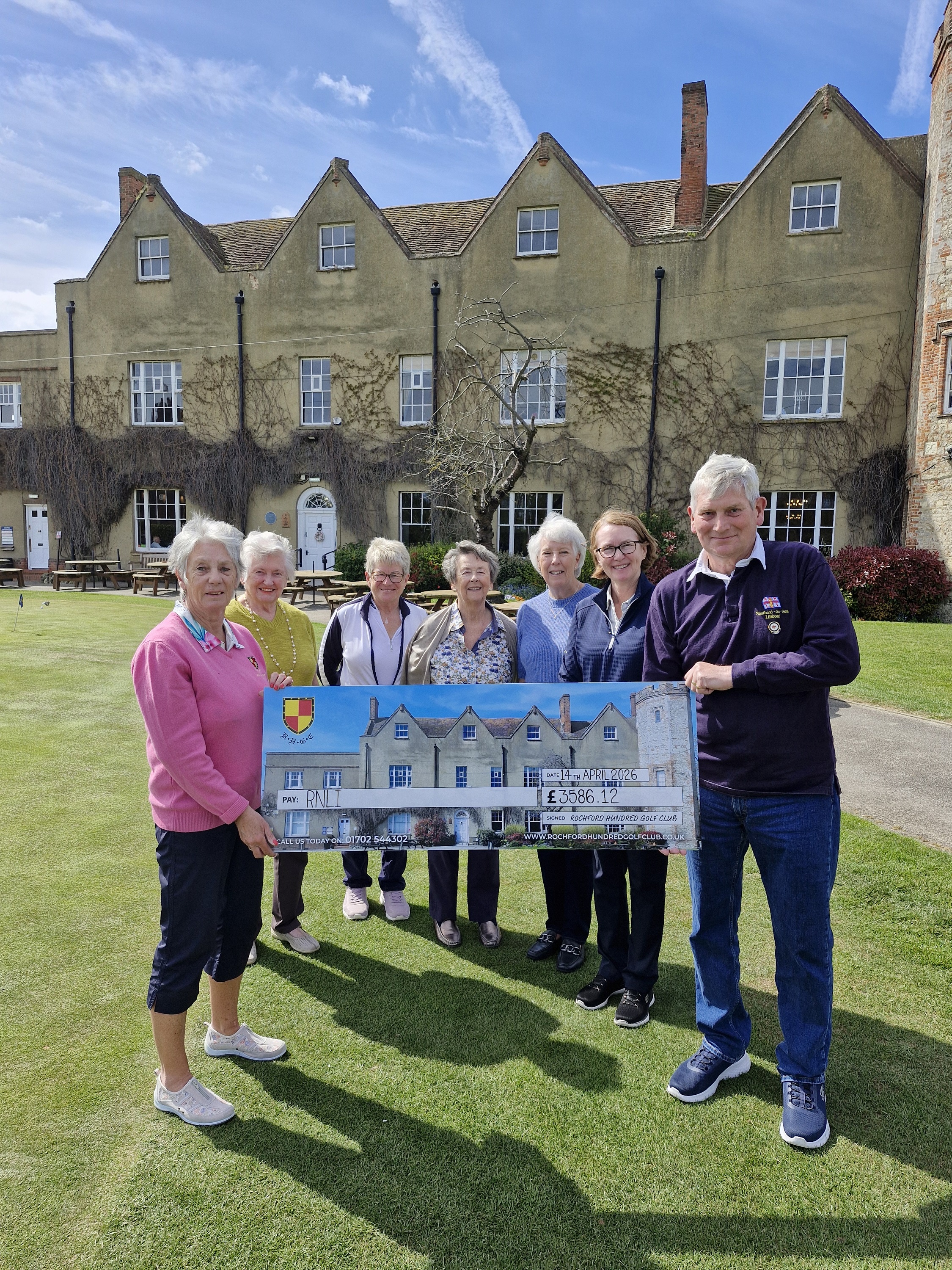 The ladies presenting the funds raised to Tony Clarke in front of the historic golf club building