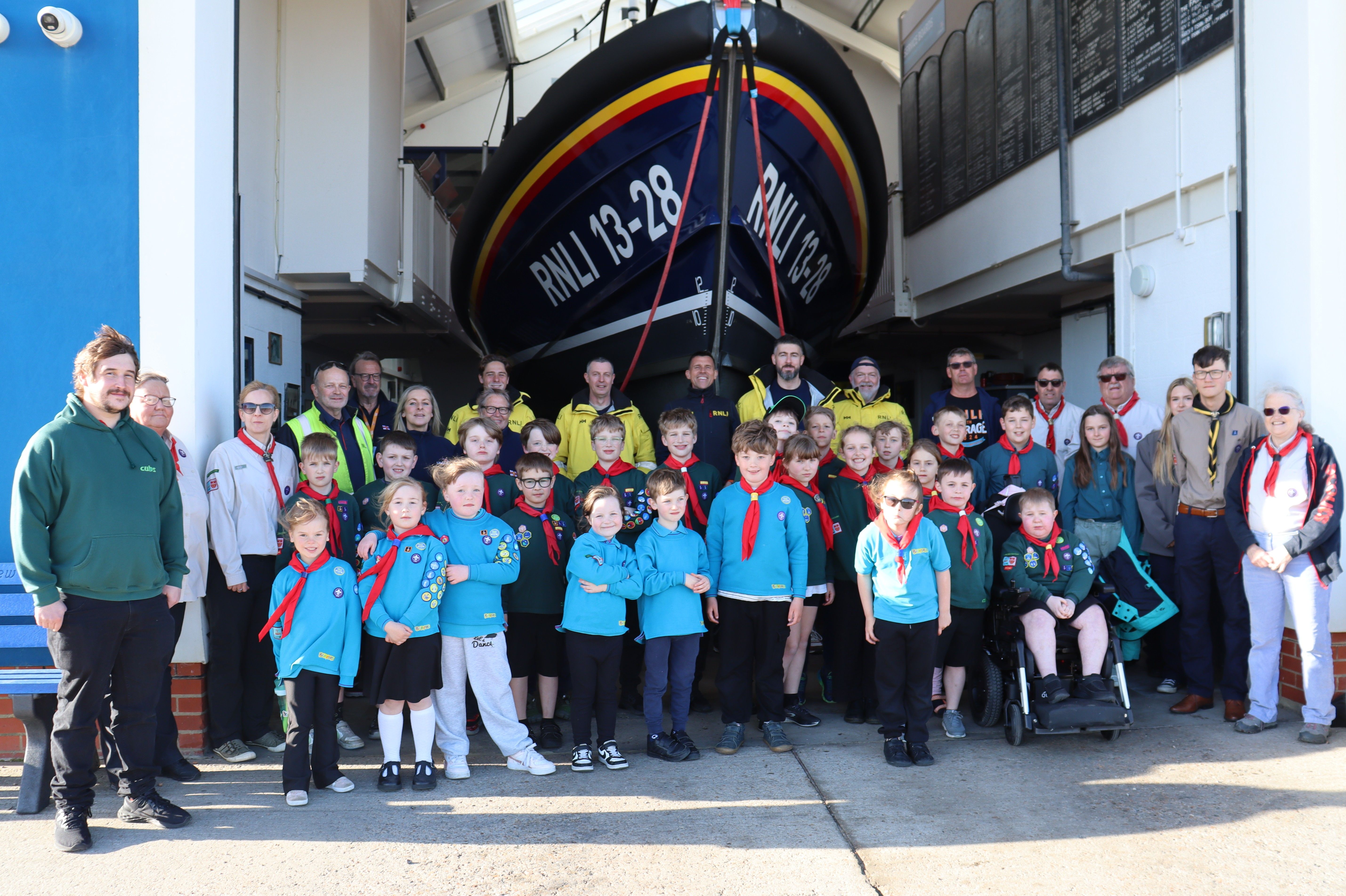 A large group of scouts and RNLI crew, all in their appropriate uniform, in front of Hastings Shannon lifeboat