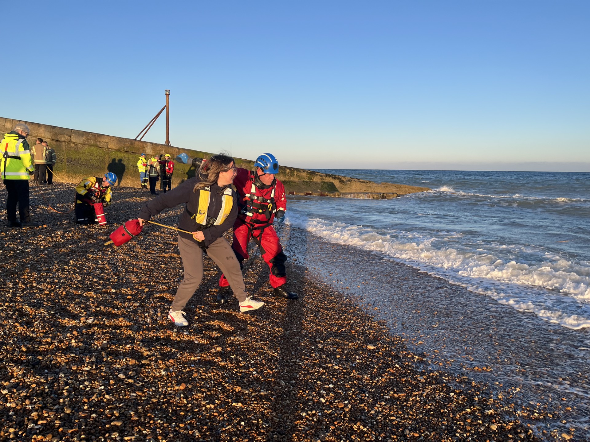 Female lifeboat volunteer being shown how to throw rescue equipment to casualty in the water