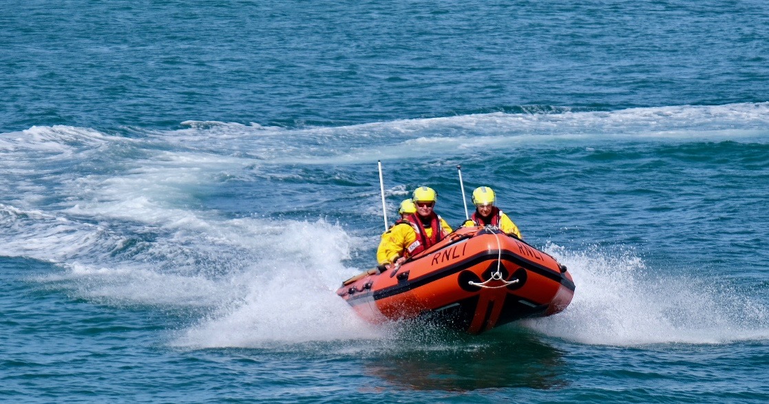 three crew on the inshore lifeboat, Sue, on a water demonstration 