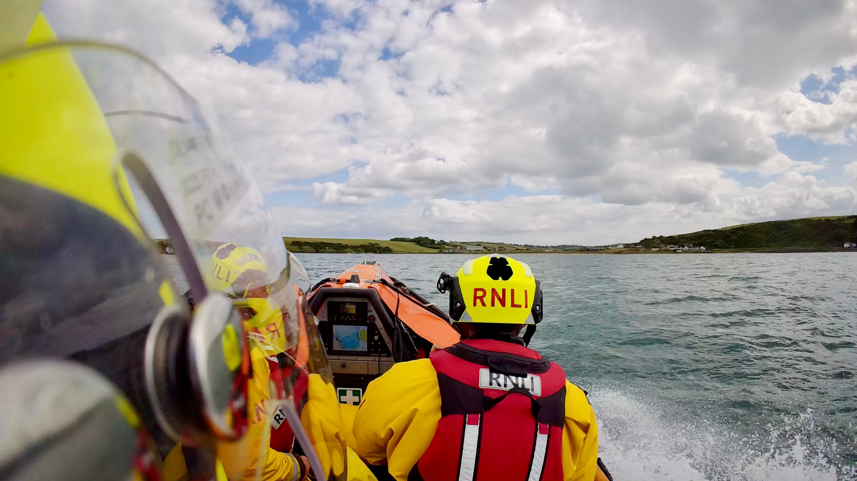 RNLI inshore lifeboat Terry with crew members onboard travelling toward Browns Bay
