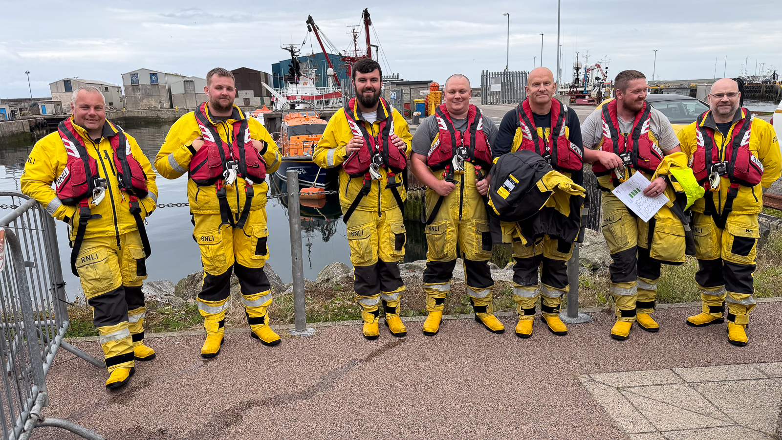 A line up of Fraserburgh RNLI volunteer crew, with Fraserburgh RNLI ALB 16-21 John Buchanan Barr moored in background at her normal berth with Jason Flett, Grant Morrison, Declan Sutherland, Scott Leye, Coxswain Gubby Duncan, mechanic Chay Cumming, and Graeme Duthie.