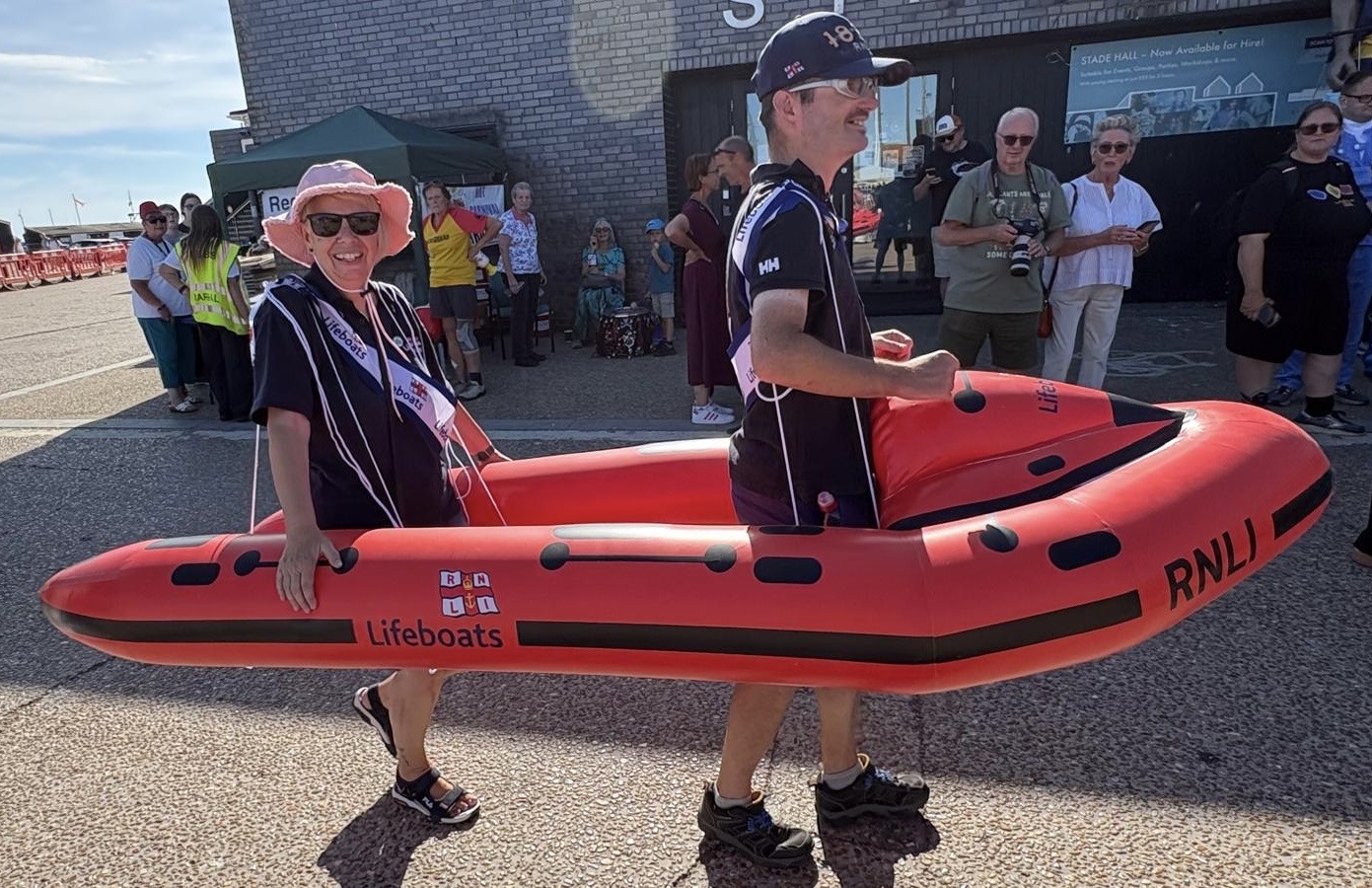 two volunteers carrying an inflatable lifeboat