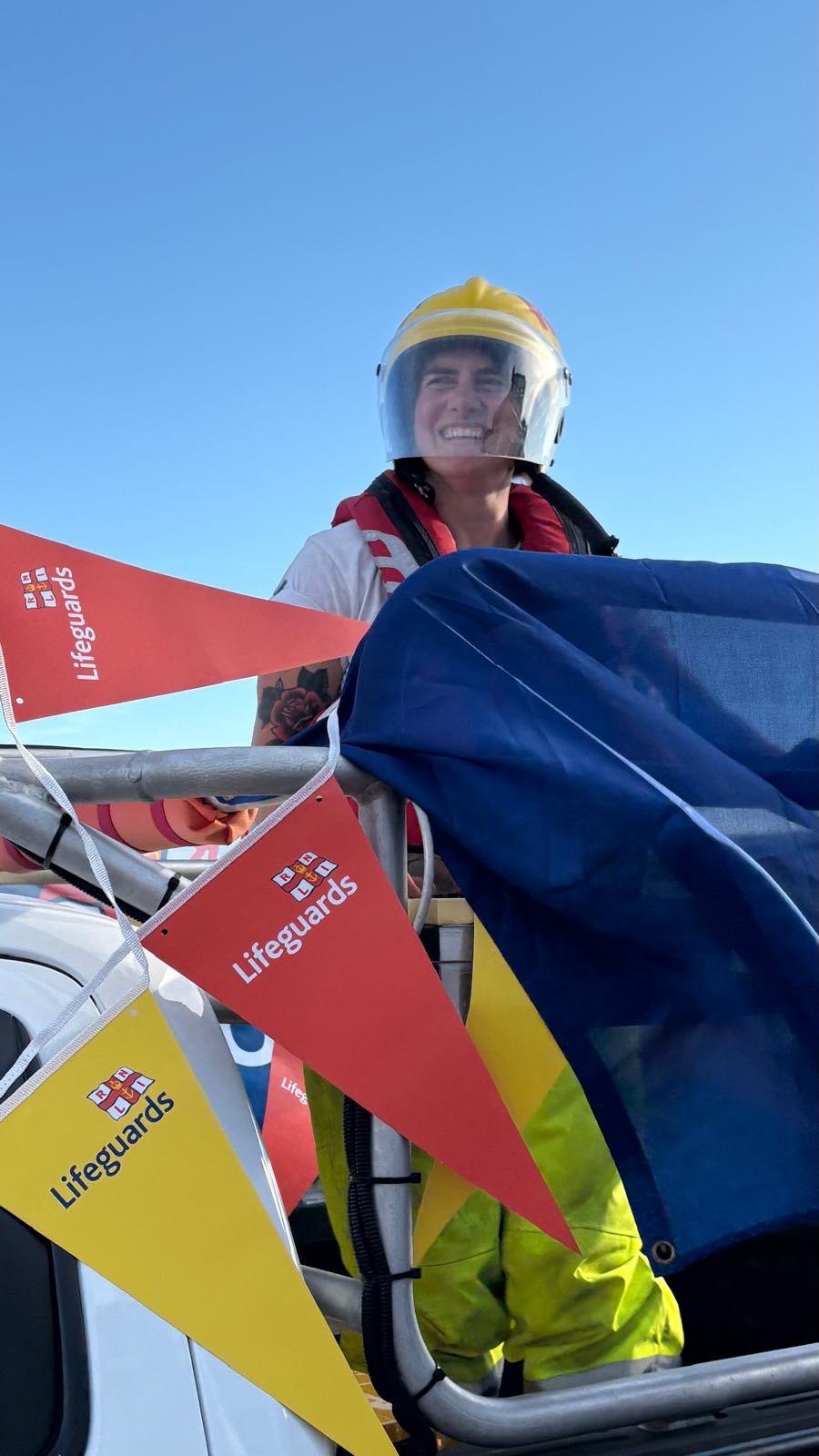 volunteer with helmet on smiling in back of lifeguard truck