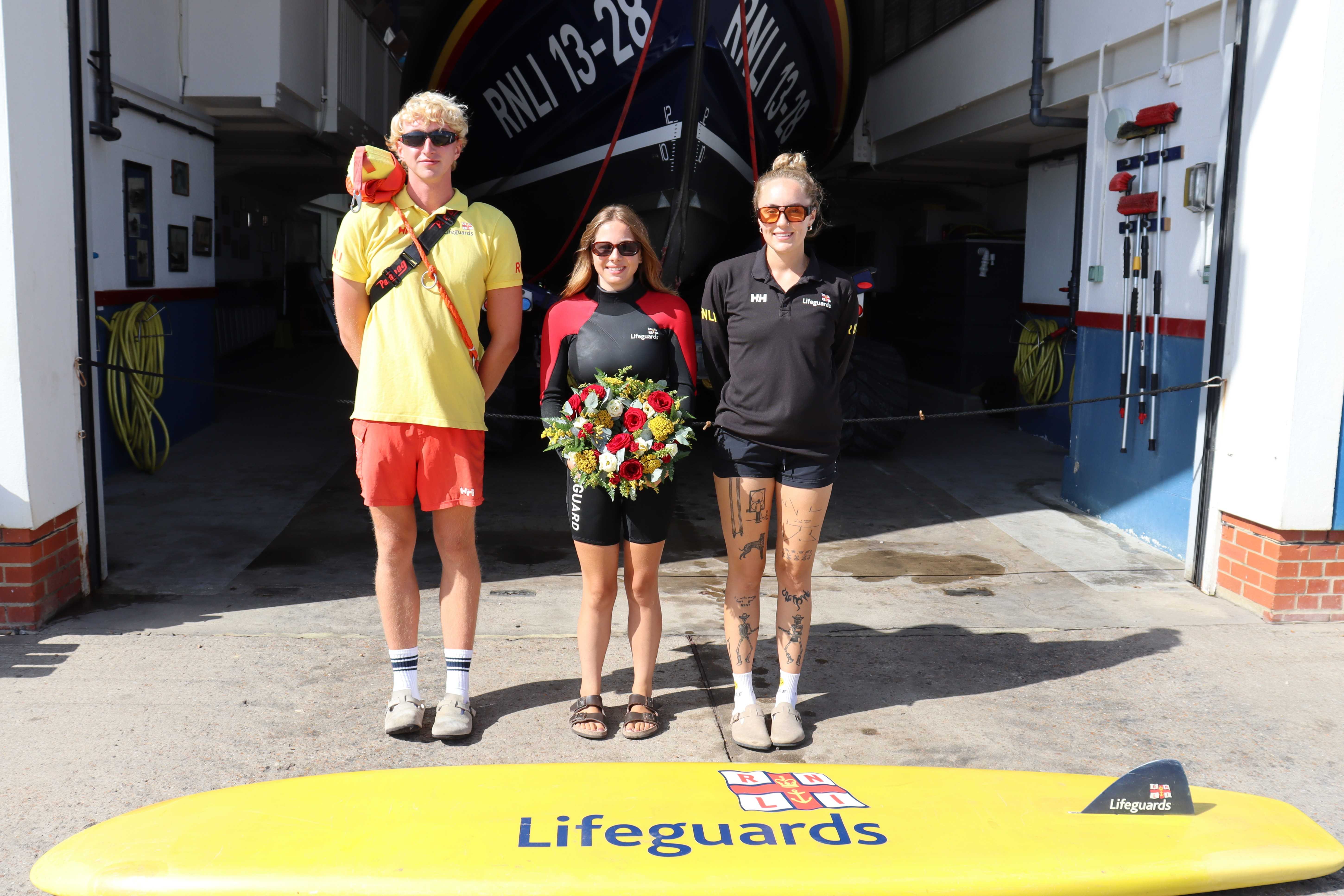 Three lifeguards in front of Hastings lifeboat station