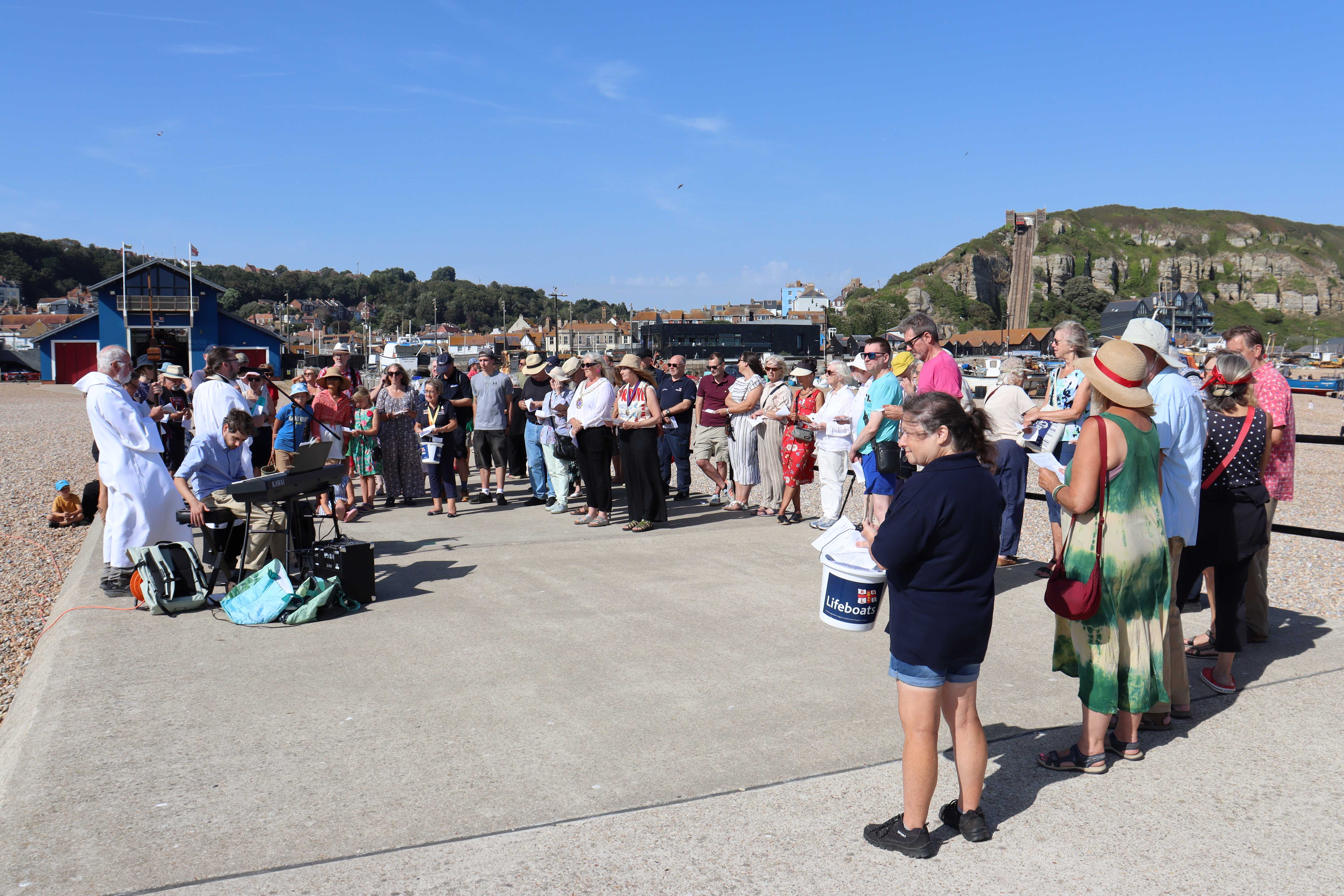 Clergy, congregation and visitors on the harbour arm in front of the lifeboat station