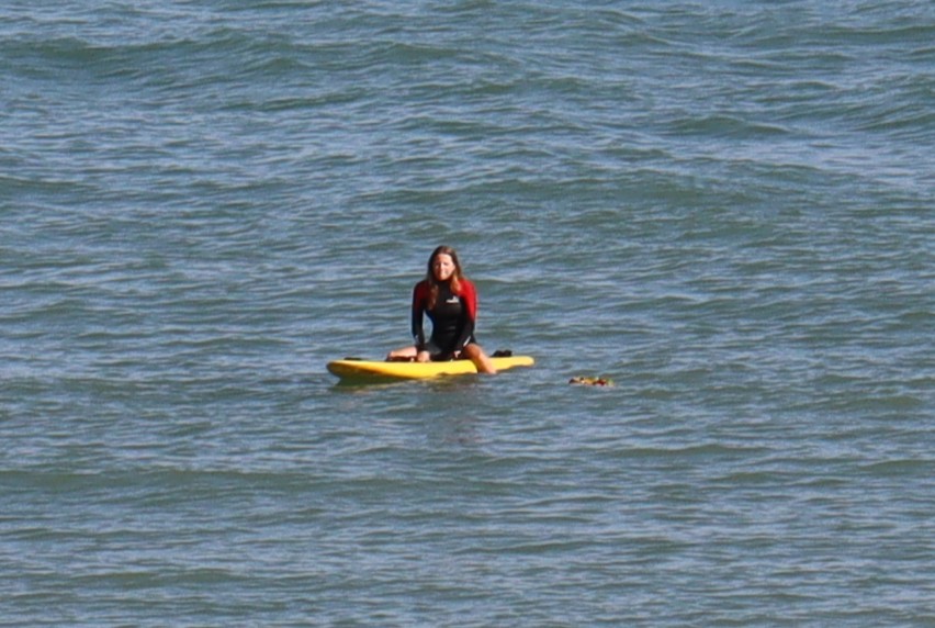 Lifeguard Amelie Holdbrook sits astride her paddleboard alongside the wreath