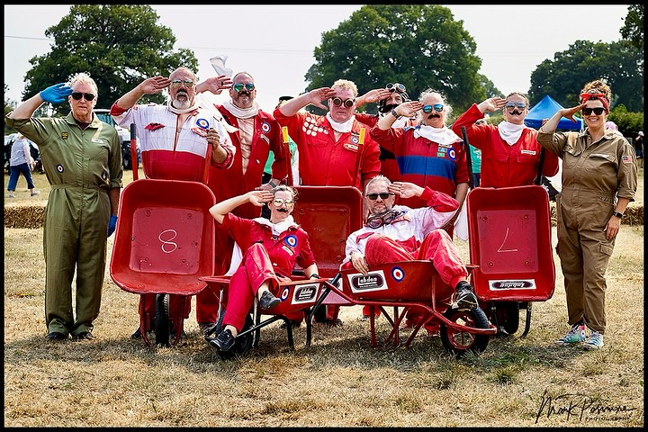 Group of men in red flight suits with red wheelbarrows