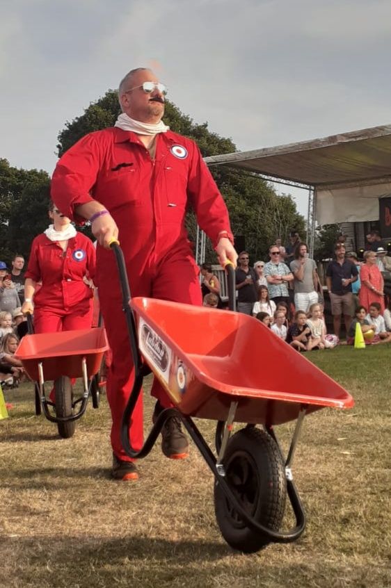 Man in red pushing a wheelbarrow