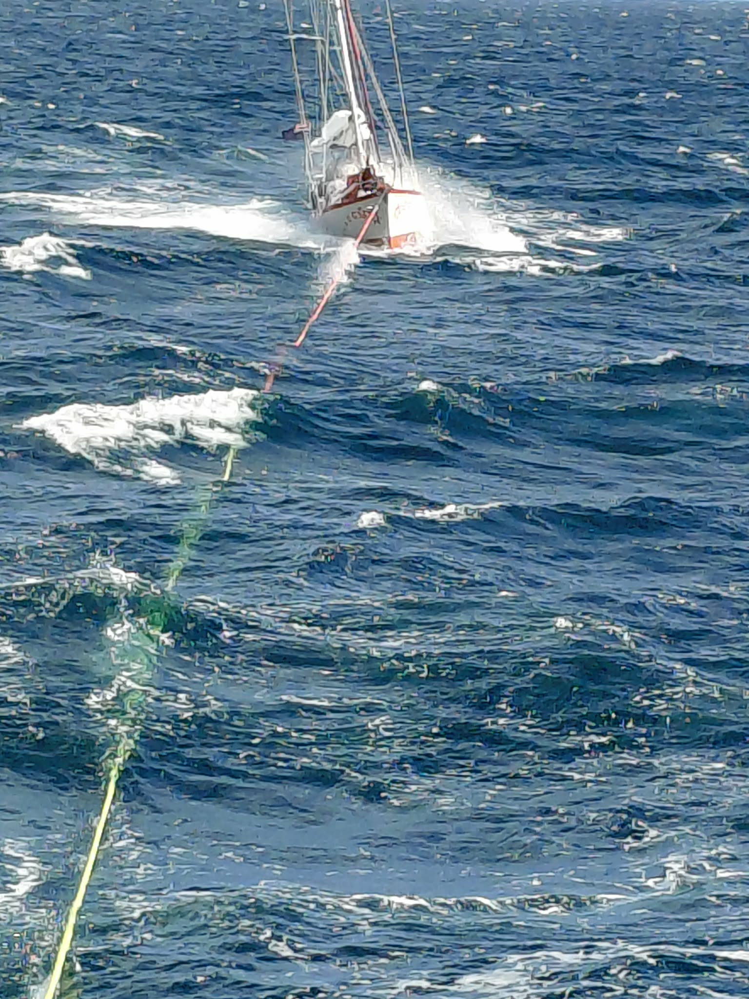 8m yacht on tow through rough seas.