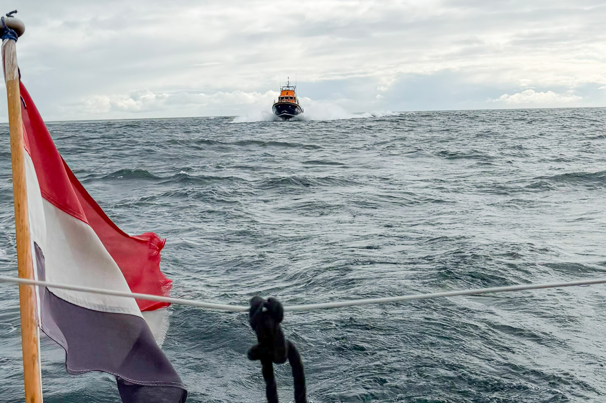 Lerwick lifeboat approaching the yacht, with a Dutch flag visible on the vessel in the foregound