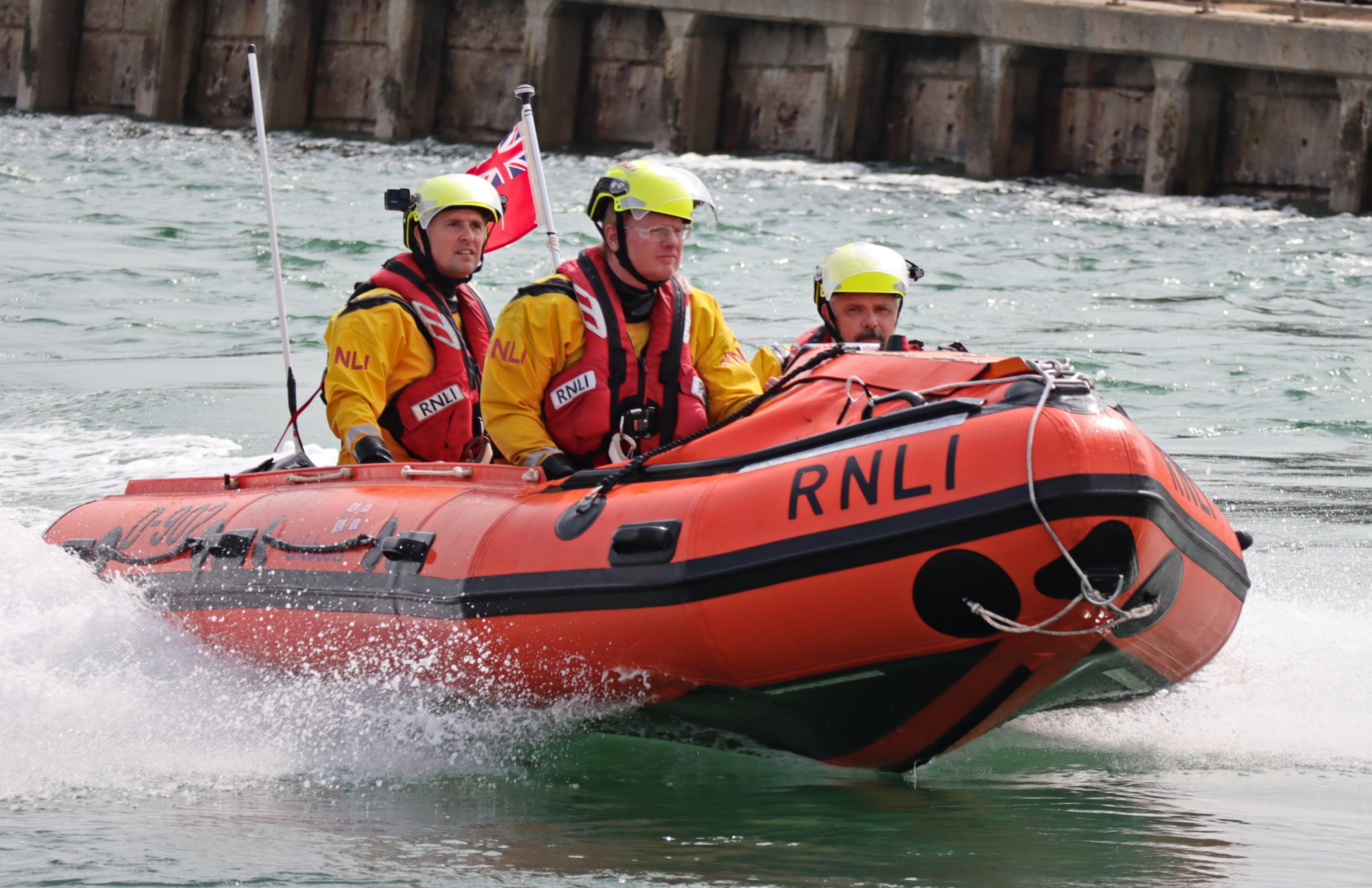 Three volunteers aboard an RNLI D-Class lifeboat