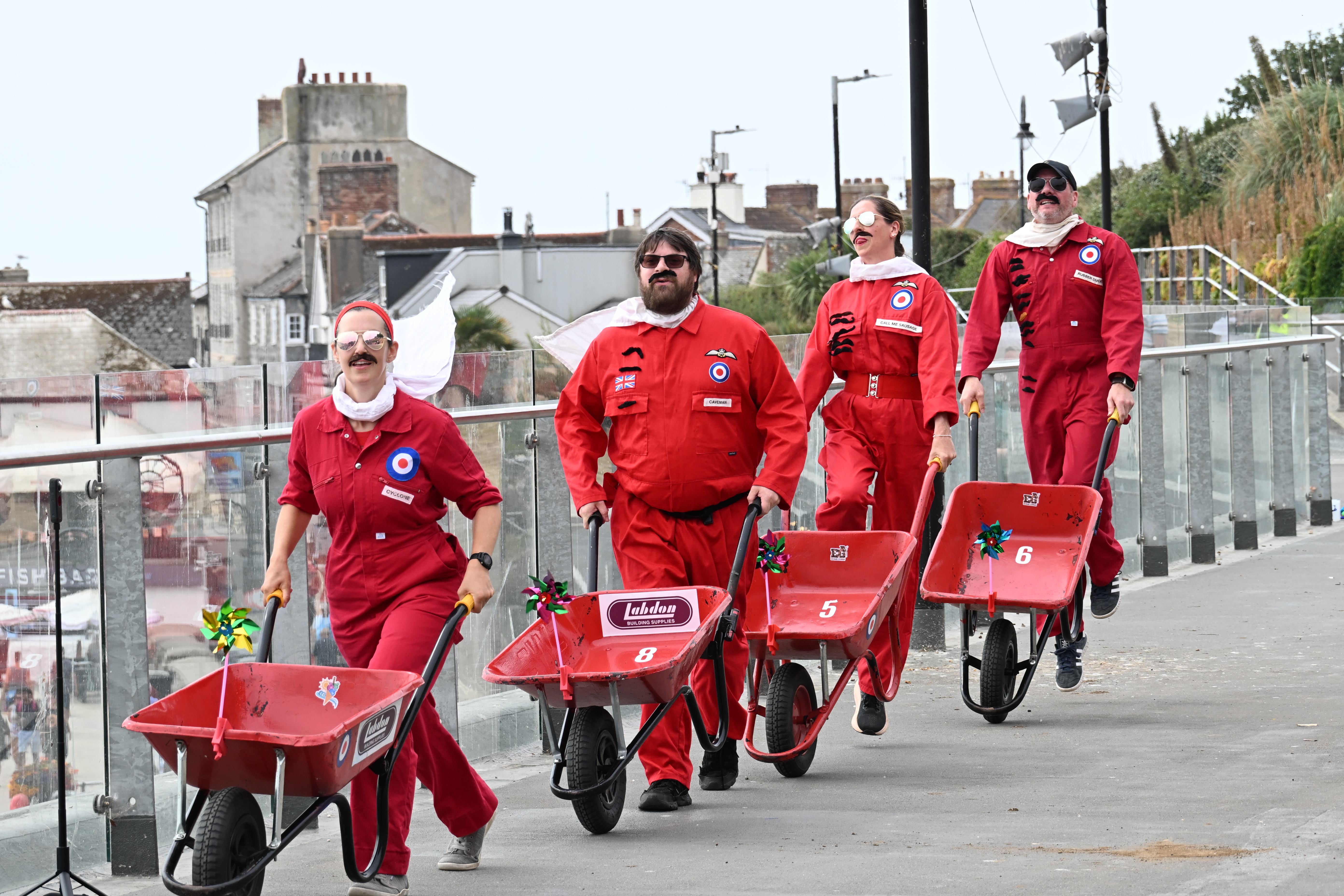 Figures in red suits with wheelbarrows