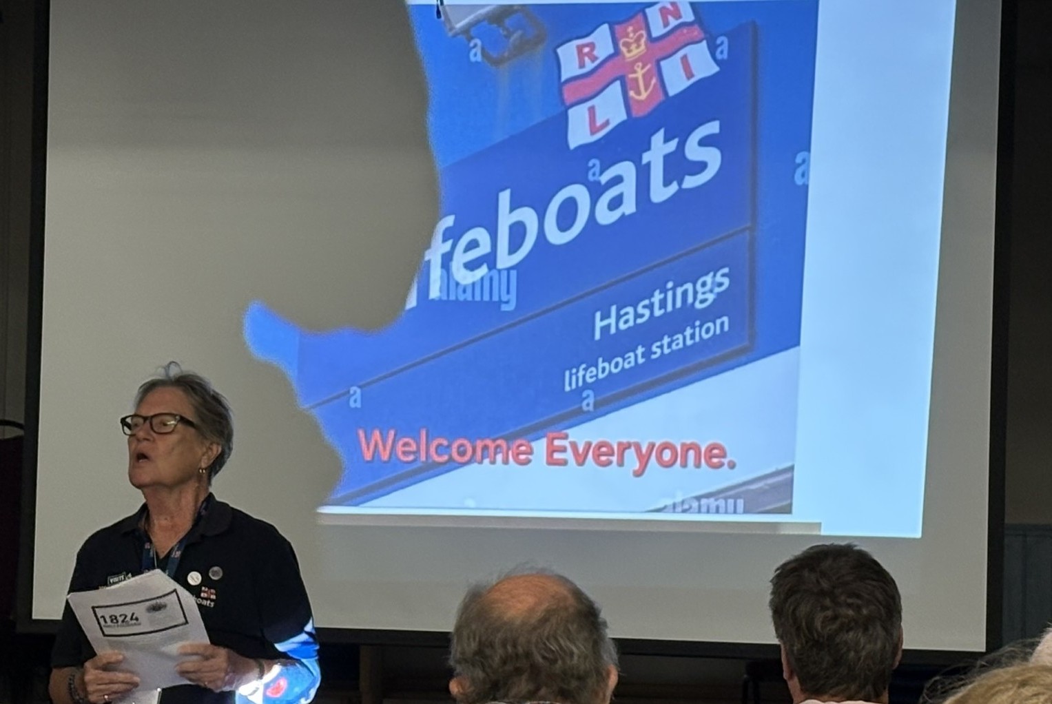 Annette Veness in RNLI kit talking in front of a screen