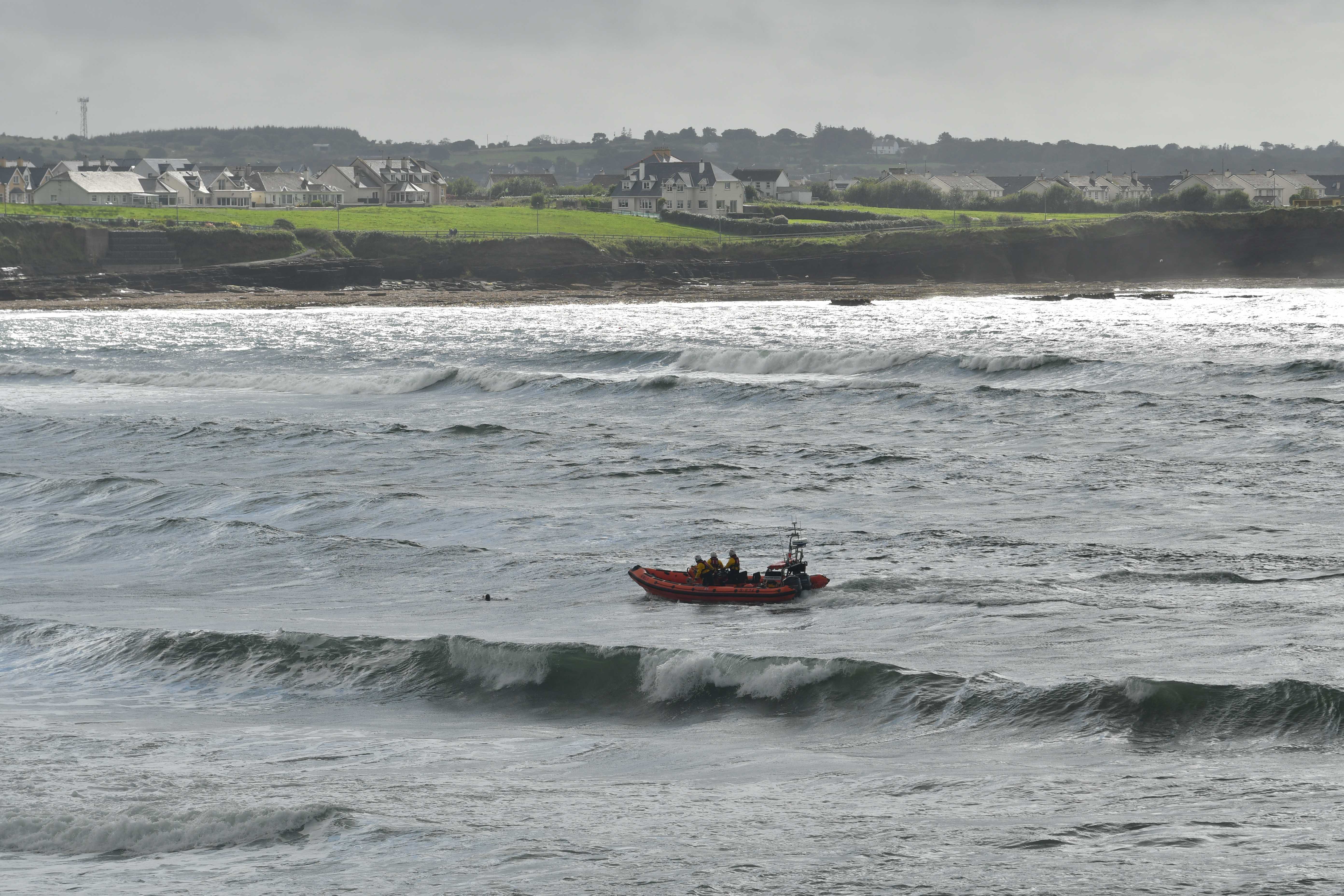 Bundoran RNLI 's lifeboat on the water with the casualty in the sea and breaking waves