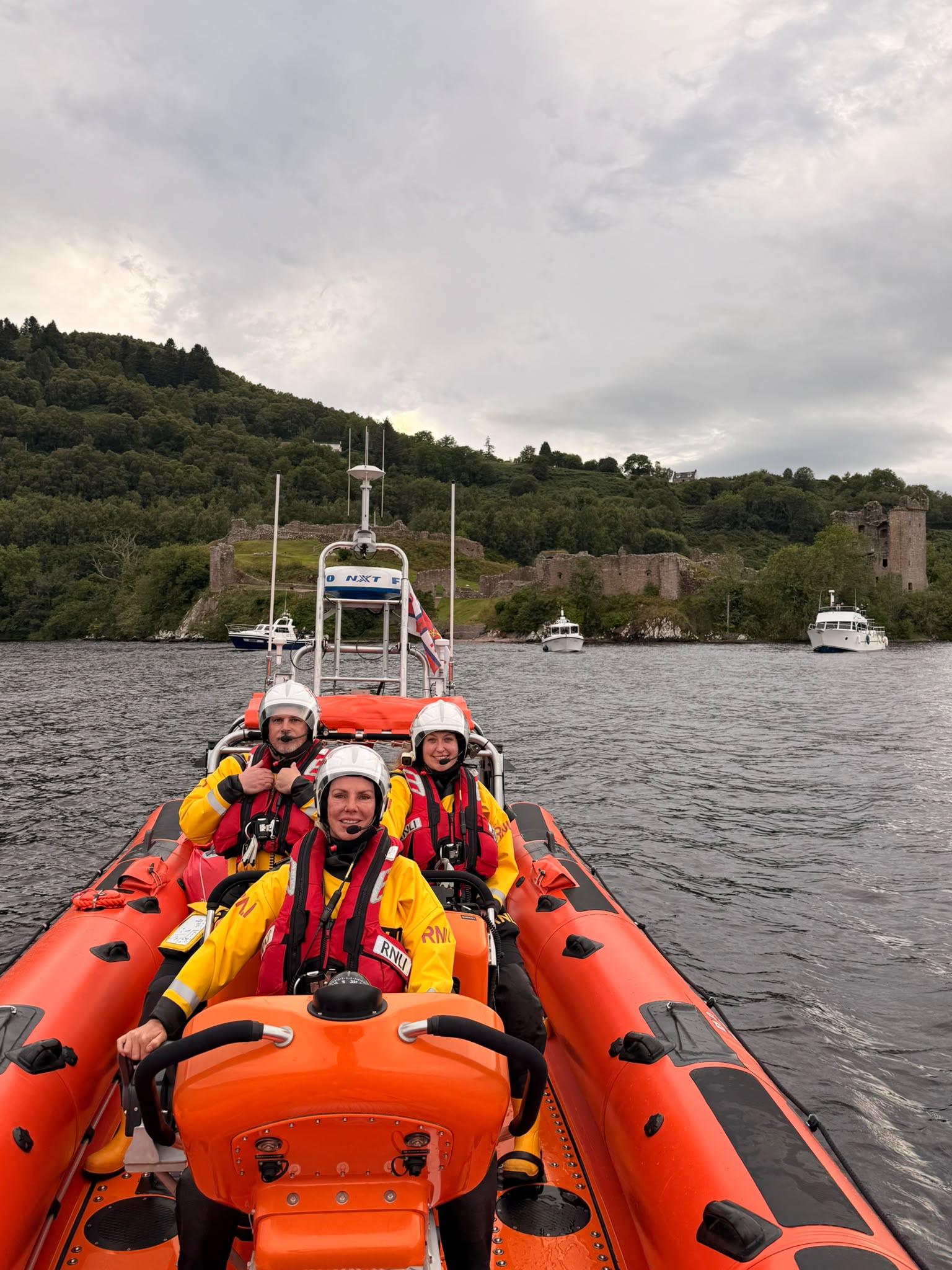 RNLI Loch Ness train in front of Urquhart Castle with commercial tour vessels