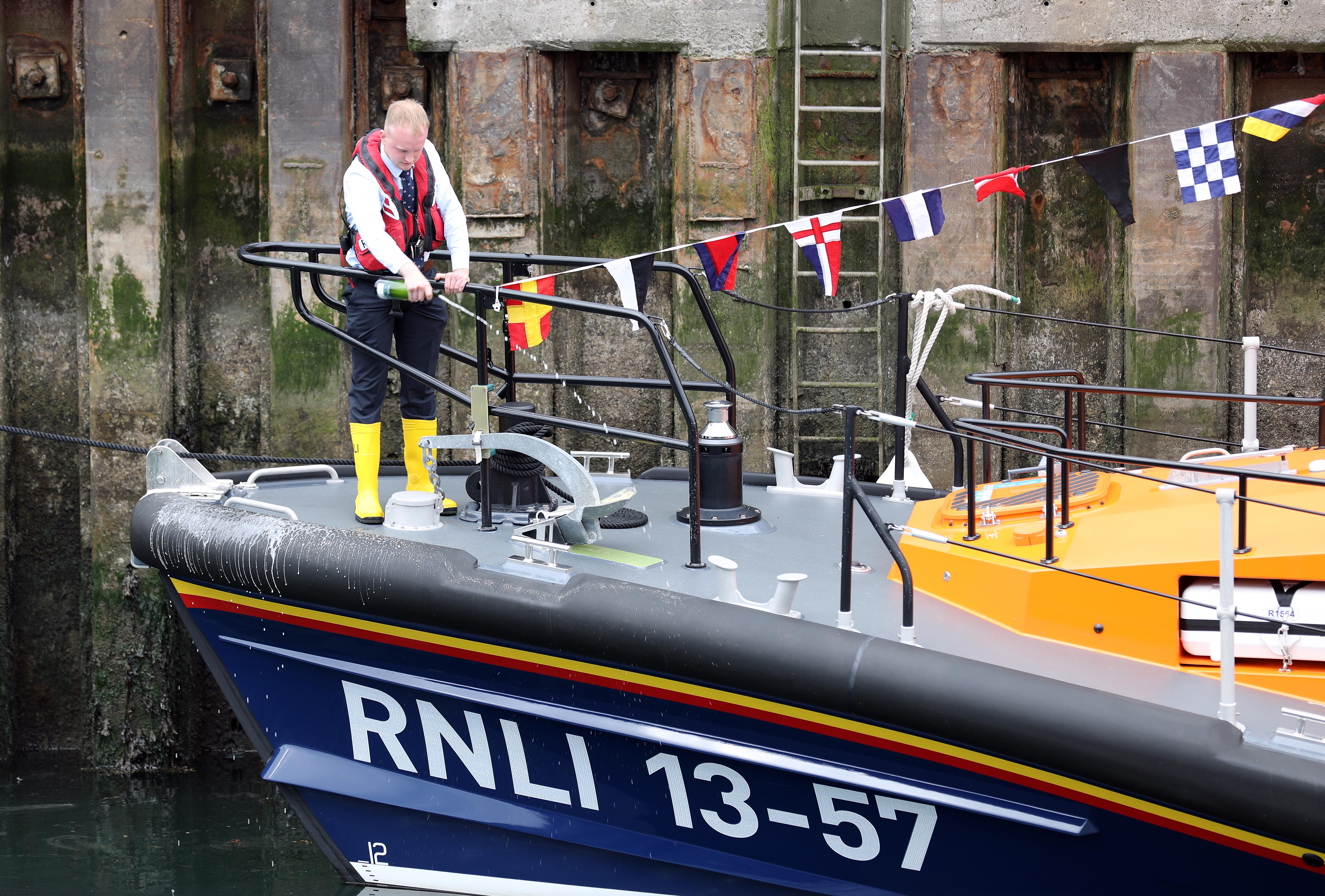 Lifeboat crewmember Andrew Young pours champagne over the Shannon lifeboat during its naming ceremony