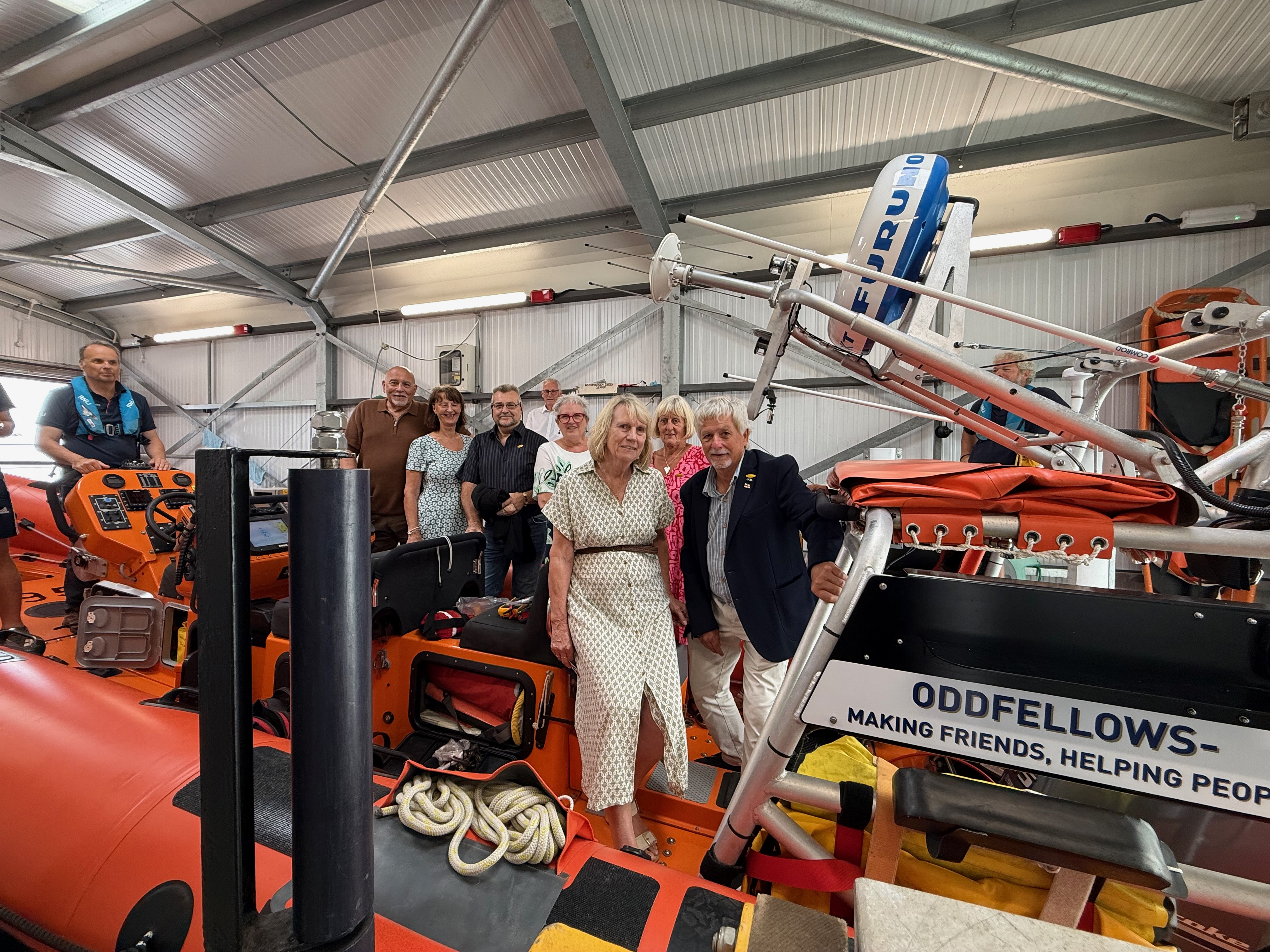 Members of the Oddfellows standing around the lifeboat they have funded, inside the boathouse at Burnham-on-Crouch RNLI