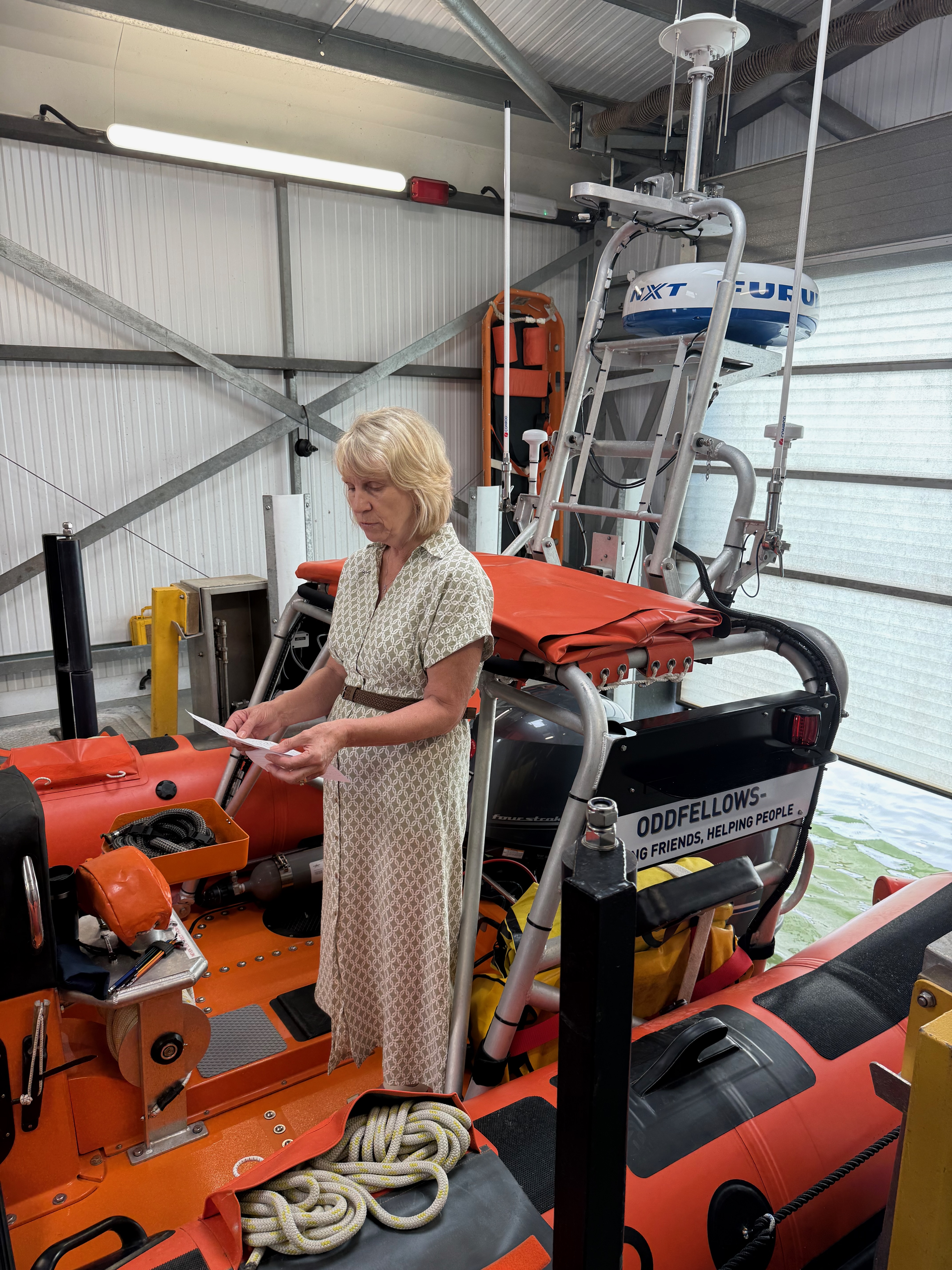 Oddfellows Society Chair, Debbie Jex giving a speech at their visit to the Atlantic 85 lifeboat. She is standing in the lifeboat which is inside the boathouse and Burnham-on-Crouch RNLI