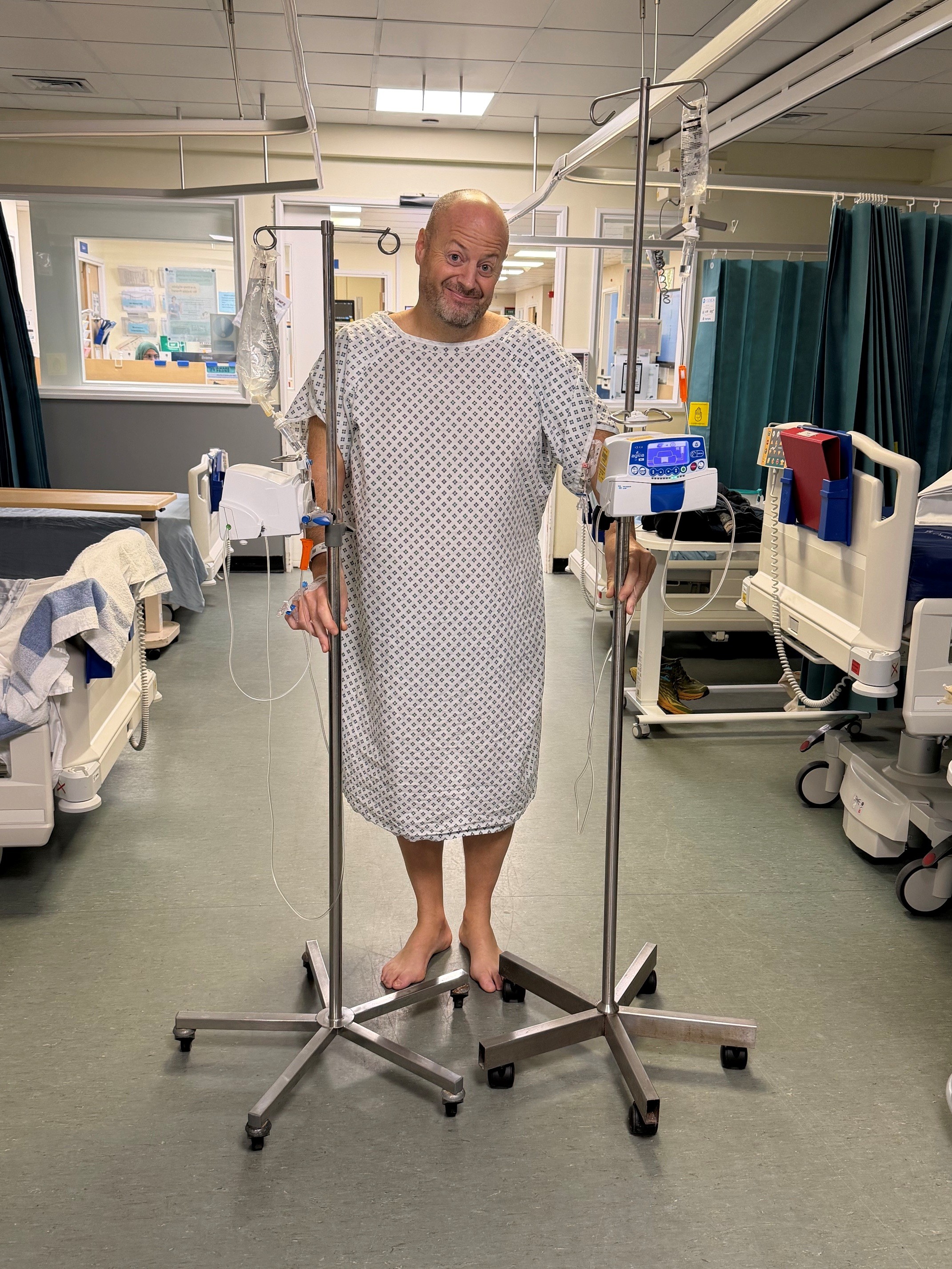 Nigel wearing a hospital gown holding to standing with fluids and heart rate monitors