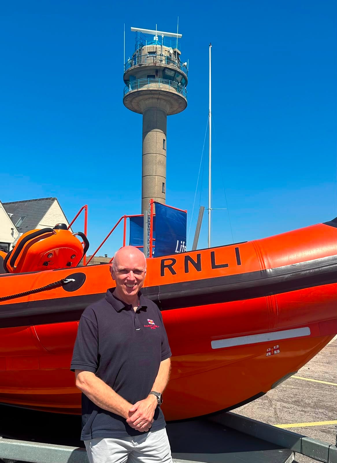 A picture of a man next to Calshot RNLI's Atlantic 85 Lifeboat with the NCI Tower in the background