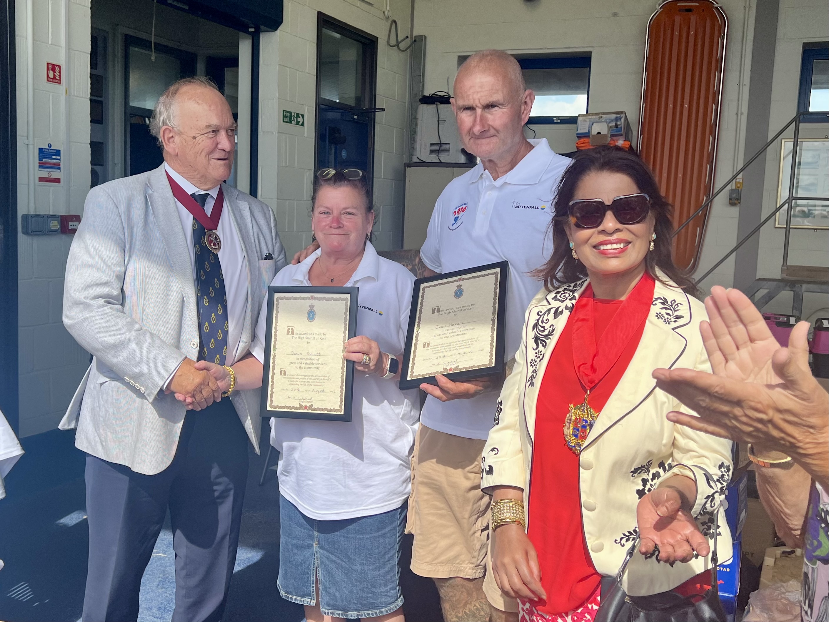 Four people with two being presented with a framed certificate.