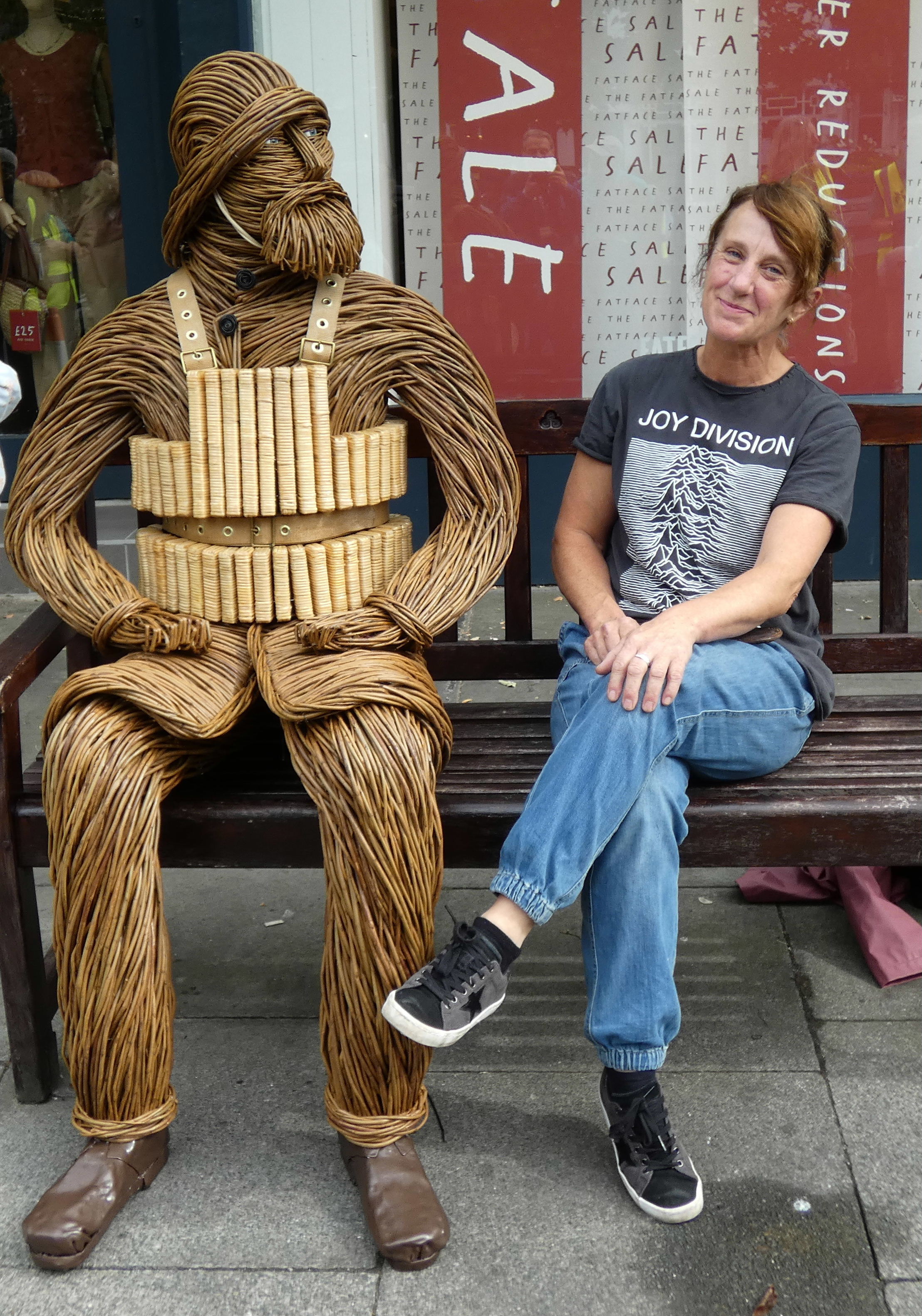 a wicker image of a Lifeboat man in 1886 dress and a lady sitting next to him on a bench