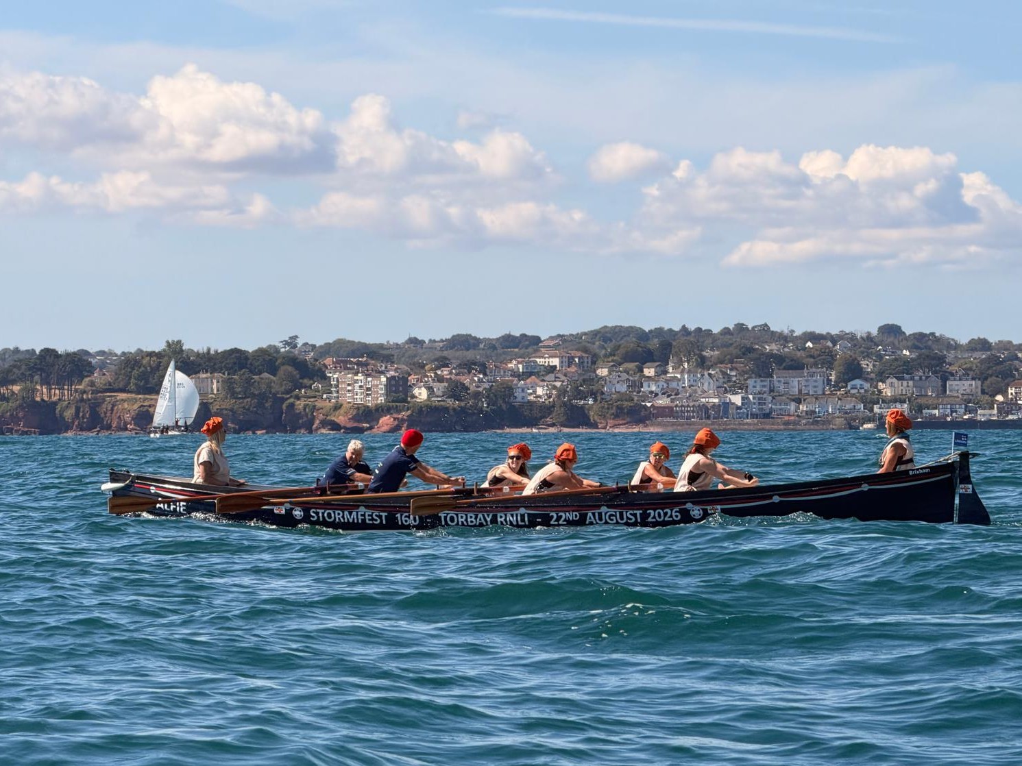 The wrapped gig boat being rowed across Tor Bay