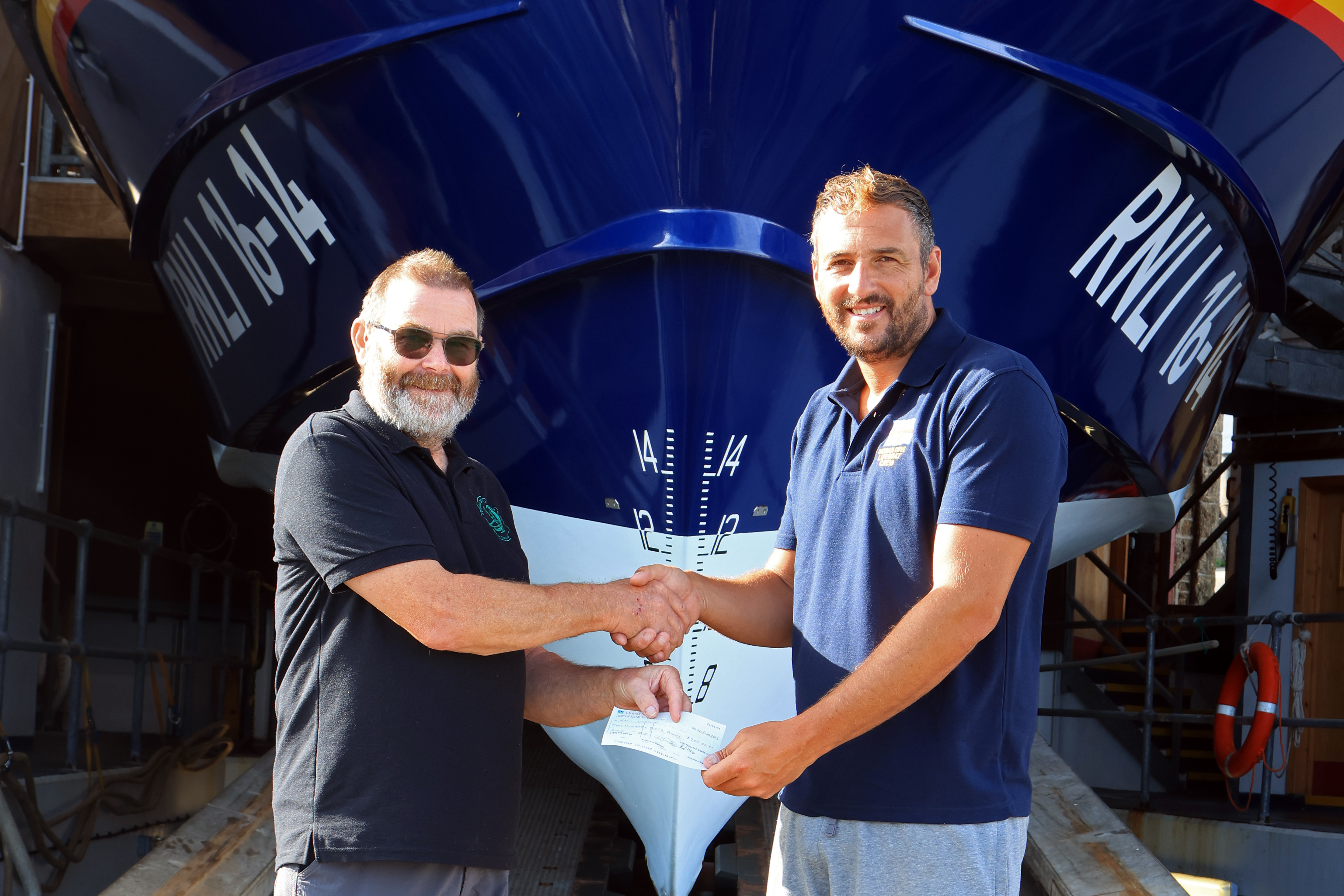 The photo shows Richard Uren presenting the cheque to Sennen Cove Coxswain Nick Hichens.