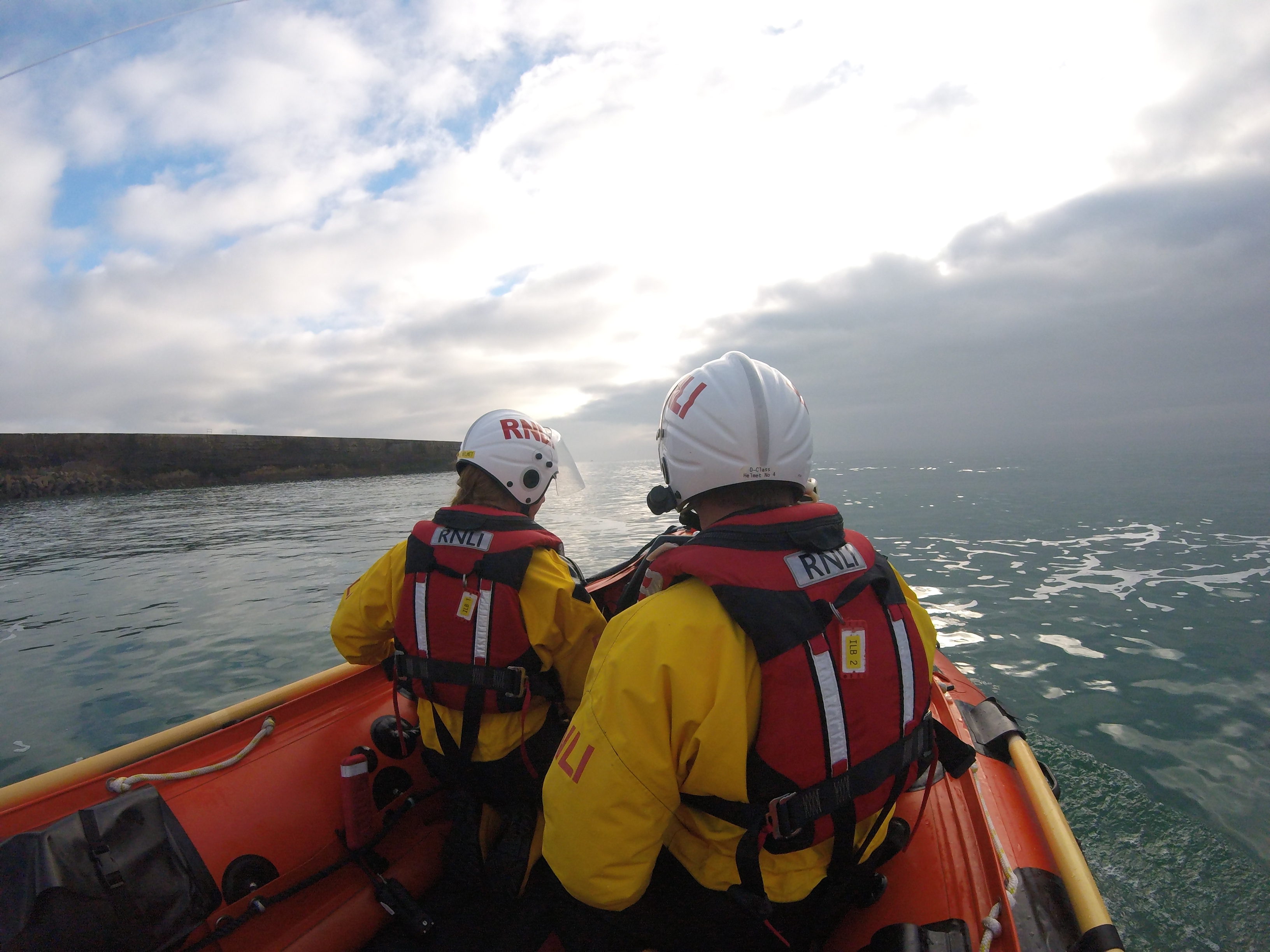 Newhaven D Class near breakwater during training Two RNLI Crew in full RNLI yellows with lifejackets. open water ahead