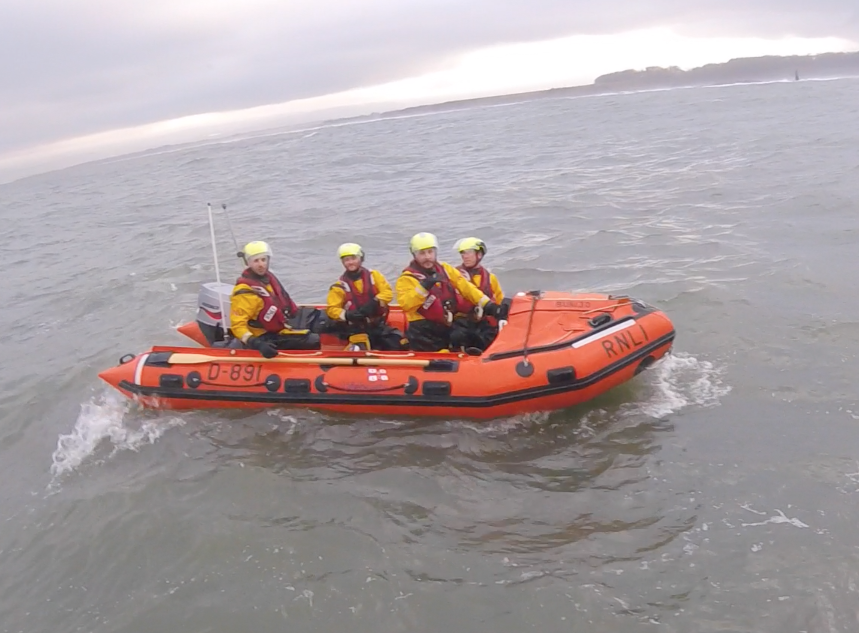 Four men in orange boat.