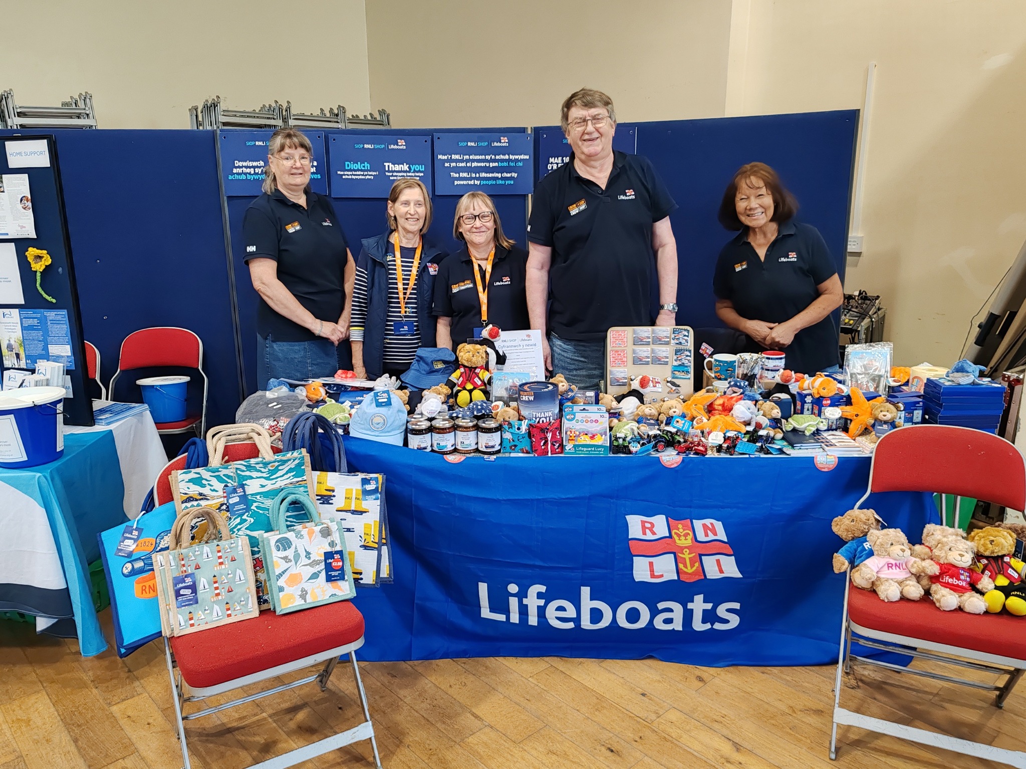 Team of Aberystwyth RNLI Shop volunteers at a stall selling products. 