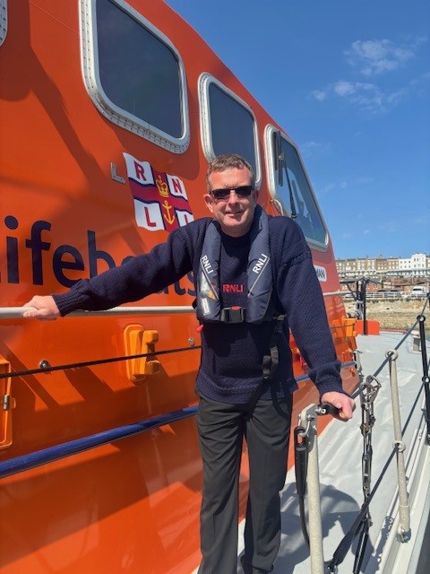 Ian Cannon Ramsgate Coxswain on board the lifeboat in Navy blue RNLI branded jumper and RNLI lifejacket. Posing holding onto the rails