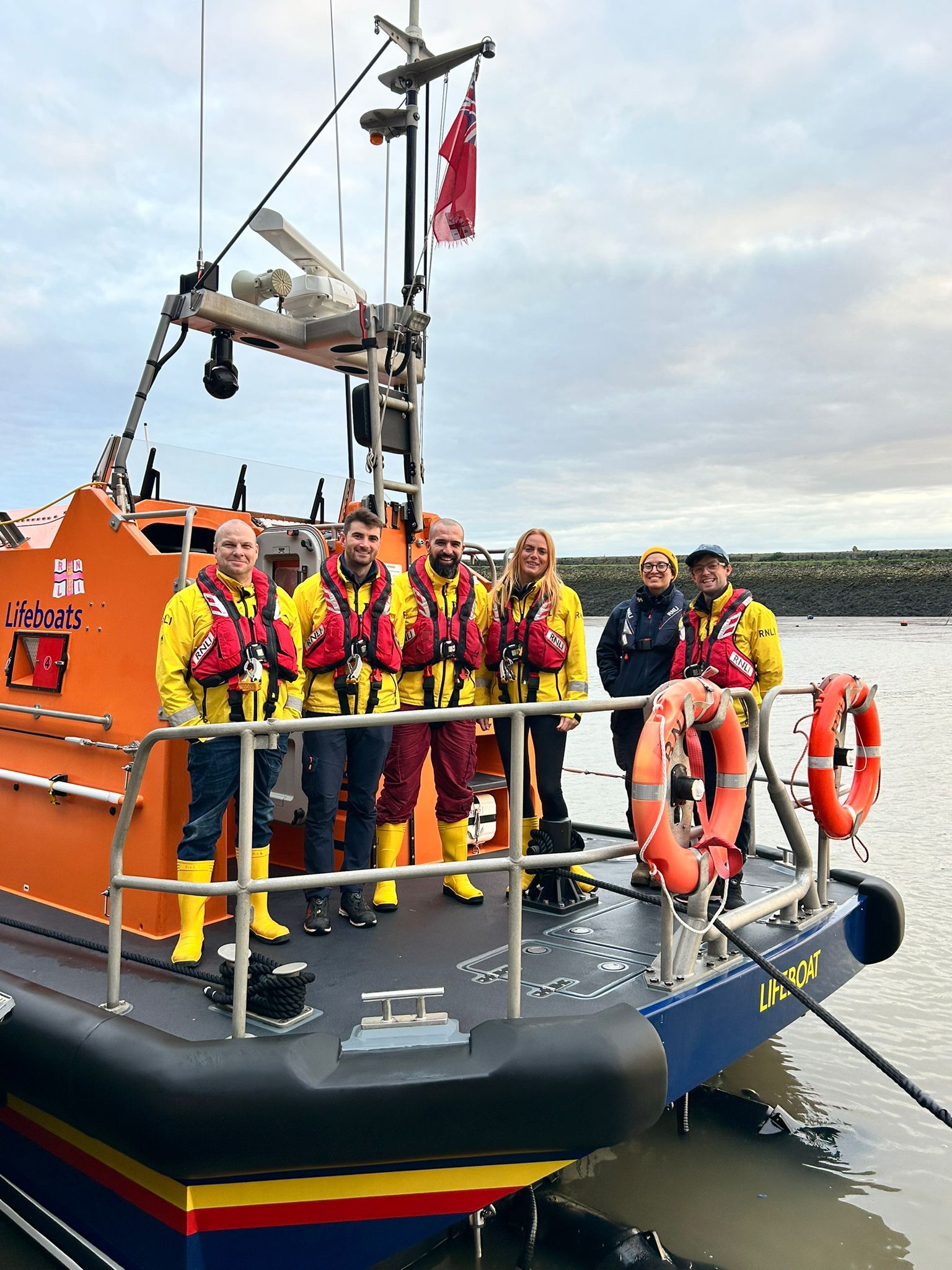 Nick and Jen stood with fellow lifeboat crew on the Shannon class lifeboat 