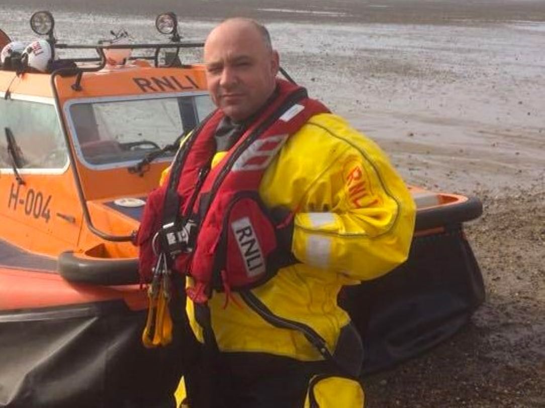 Southend RNLI volunteer Tony Bonham standing next to the inshore rescue hovercraft