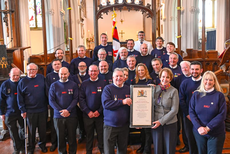 Woman presenting certificate to man with crew in the background