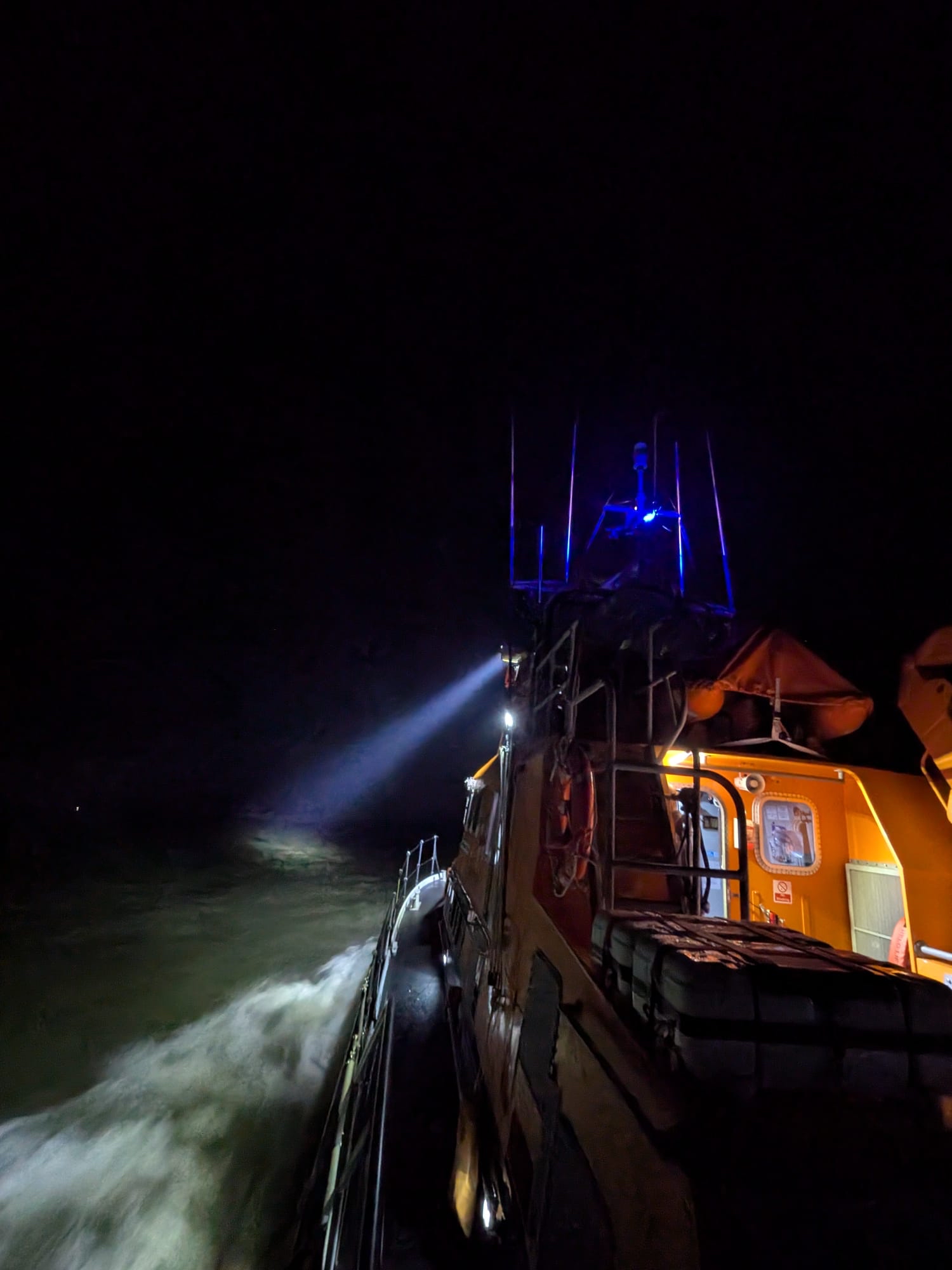 Yarmouth lifeboat out at sea at night using searchlight