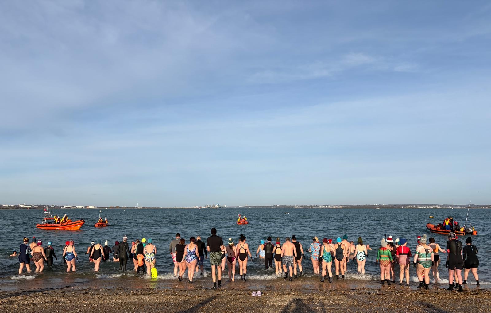 A group of people just about to enter the water for Calshot RNLI's New Year's Day Dip