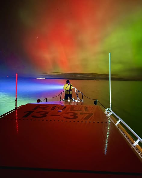 Crew Member manning Search Light under Northern Lights