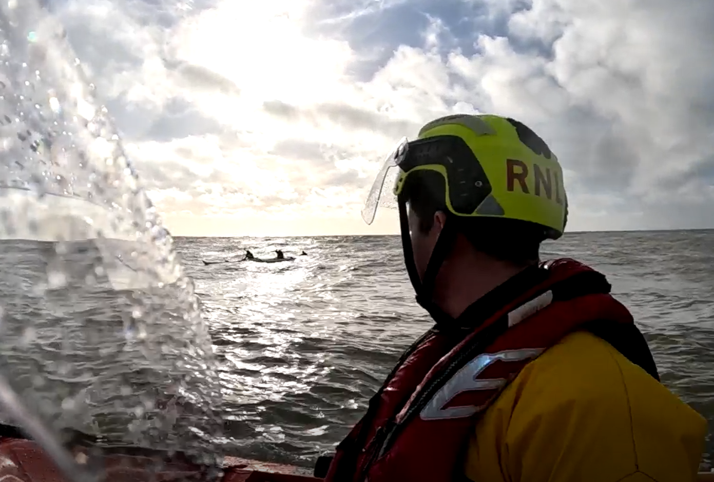 RNLI crew pictured on inshore lifeboat approaching casualties in the water.