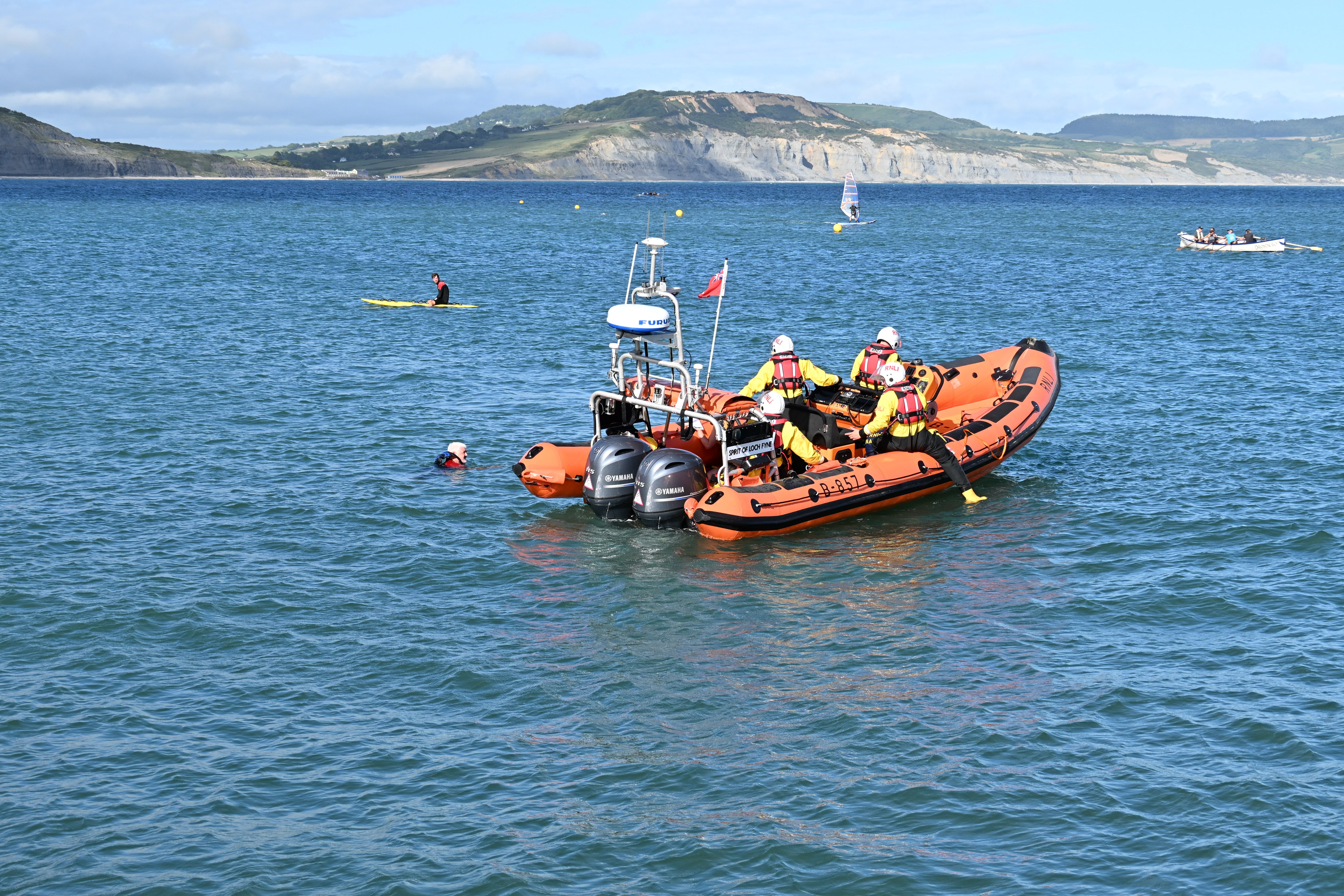 Orange lifeboat with persons in the water