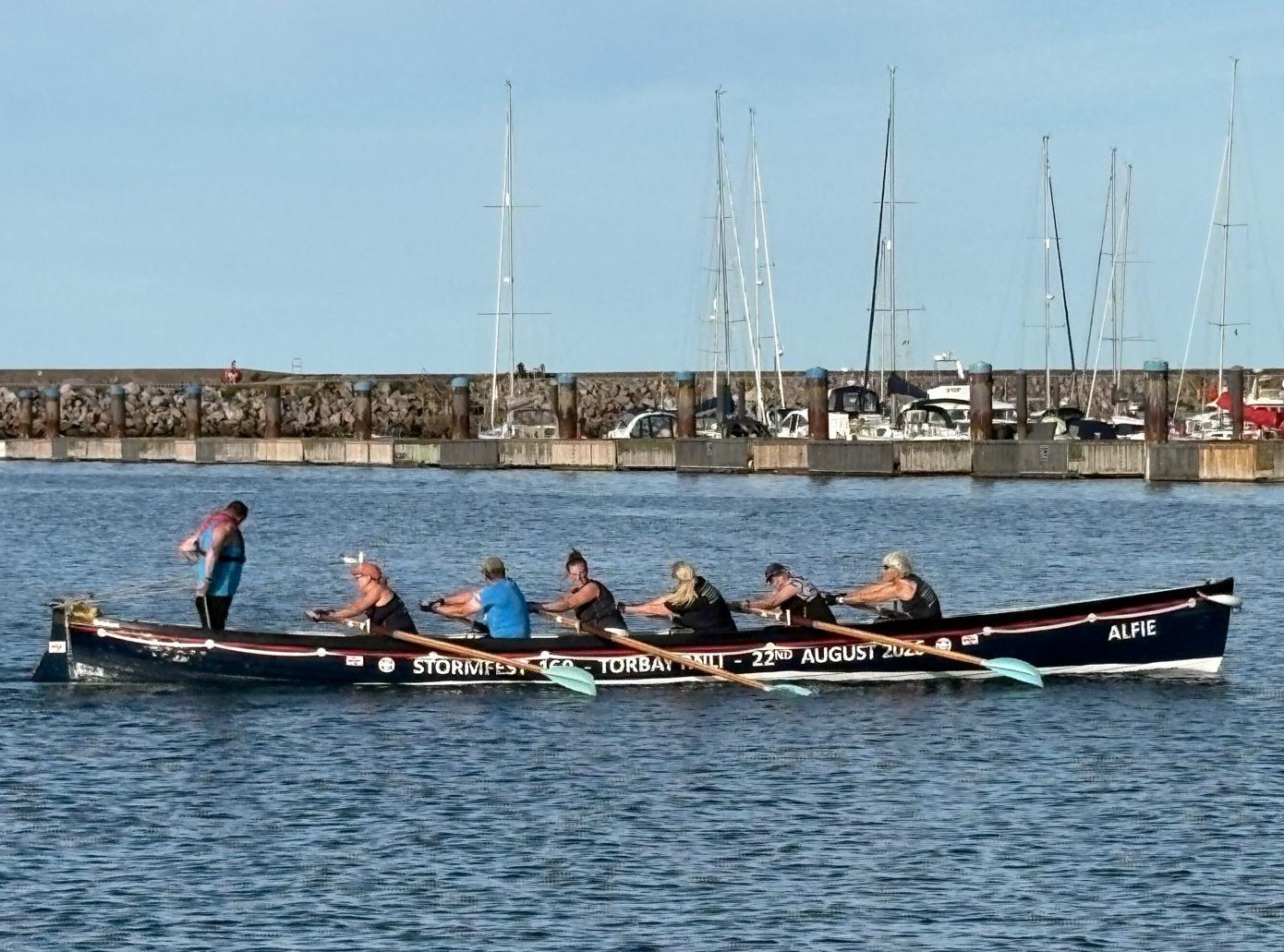 The wrapped gig boat being rowed in Brixham Harbour