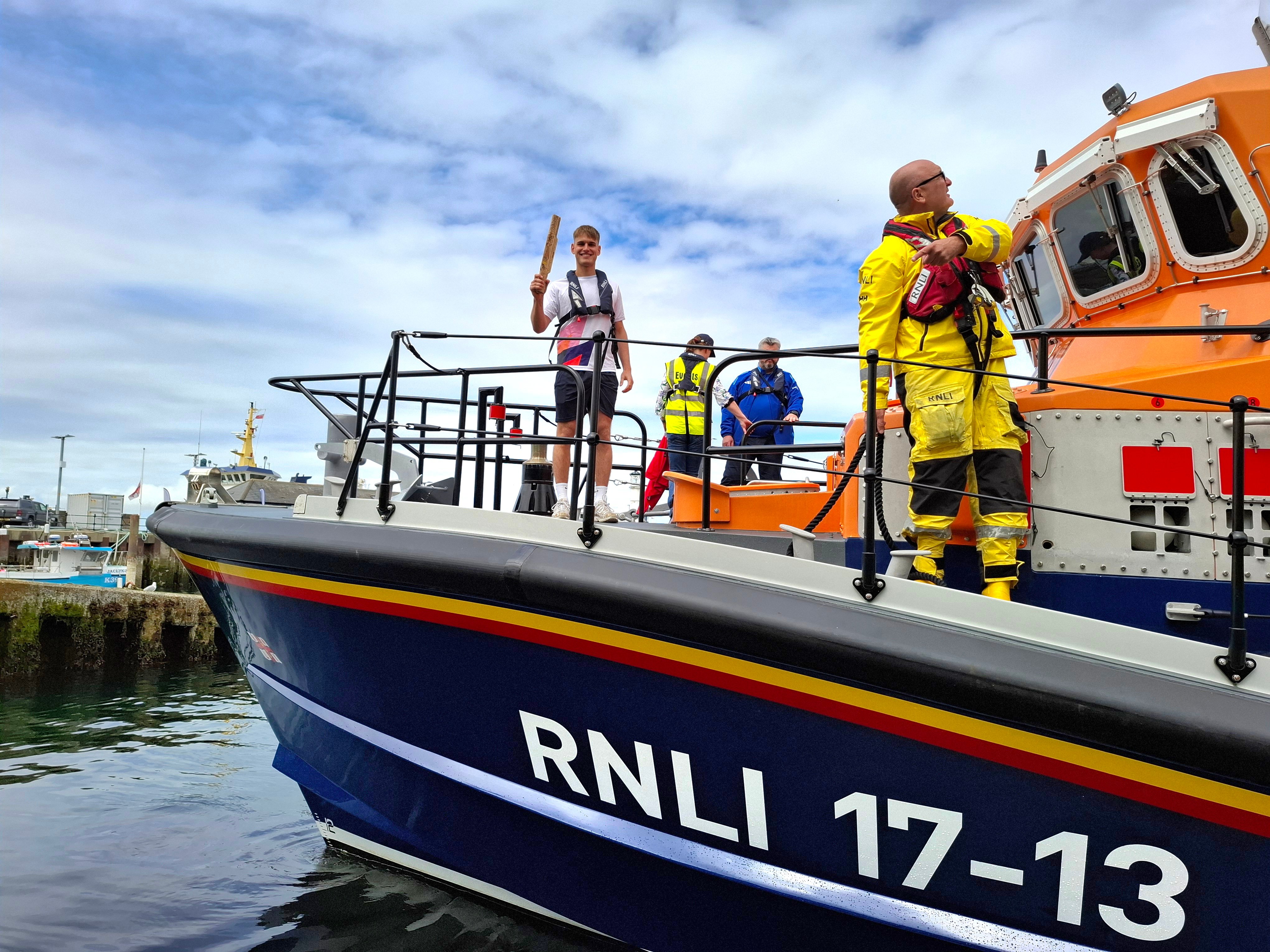 Young athlete, Finlay Scott, RNLI crew member and two other people on the bow of RNLI 17-13 all weather lifeboat.