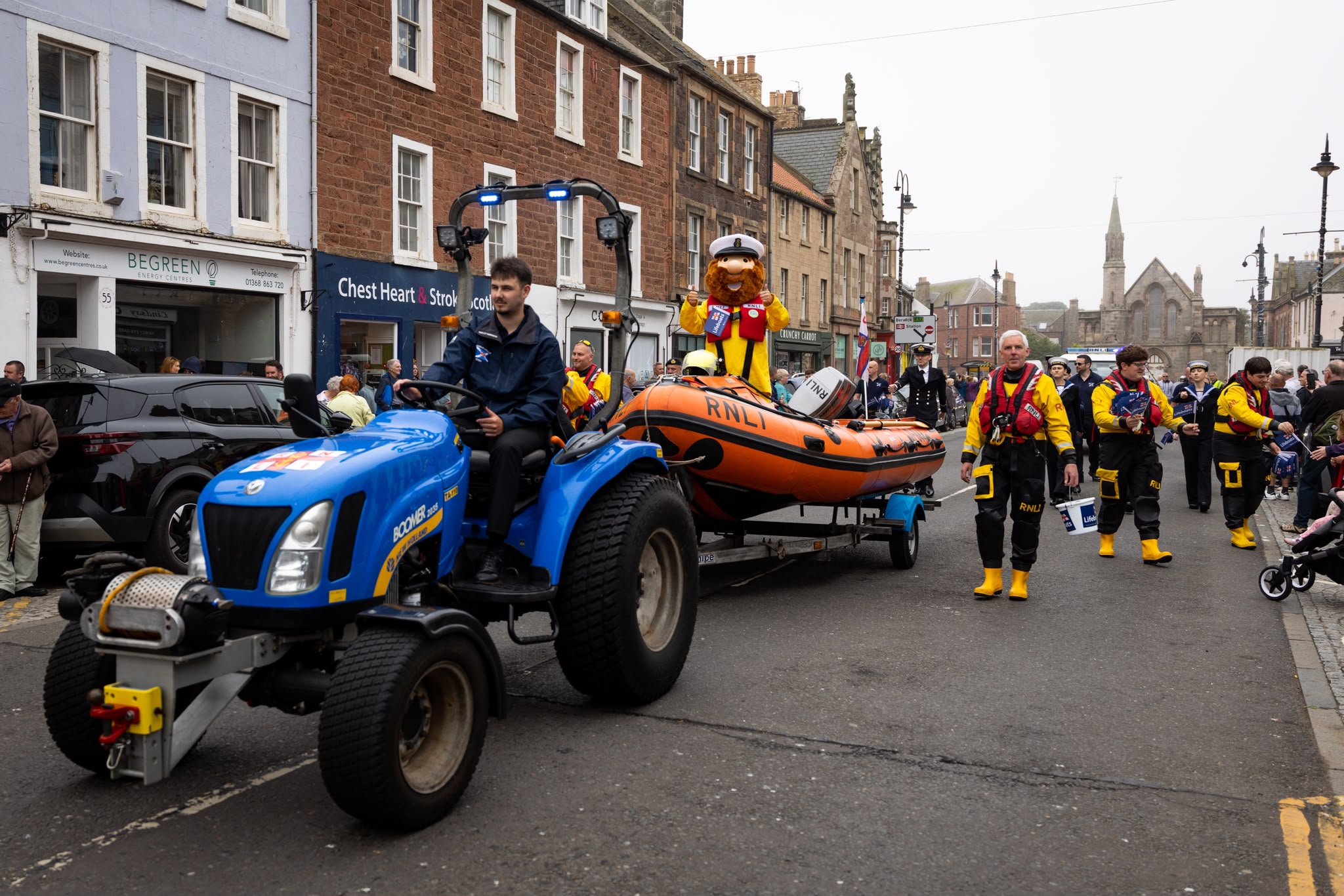 Tractor and lifeboat with people walking.