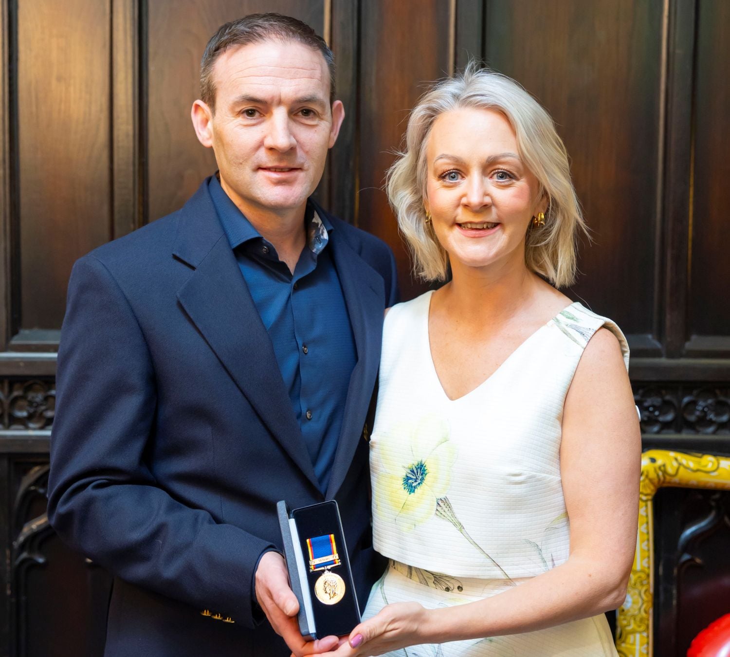 Crew member standing beside his wife holding his 30 year medal