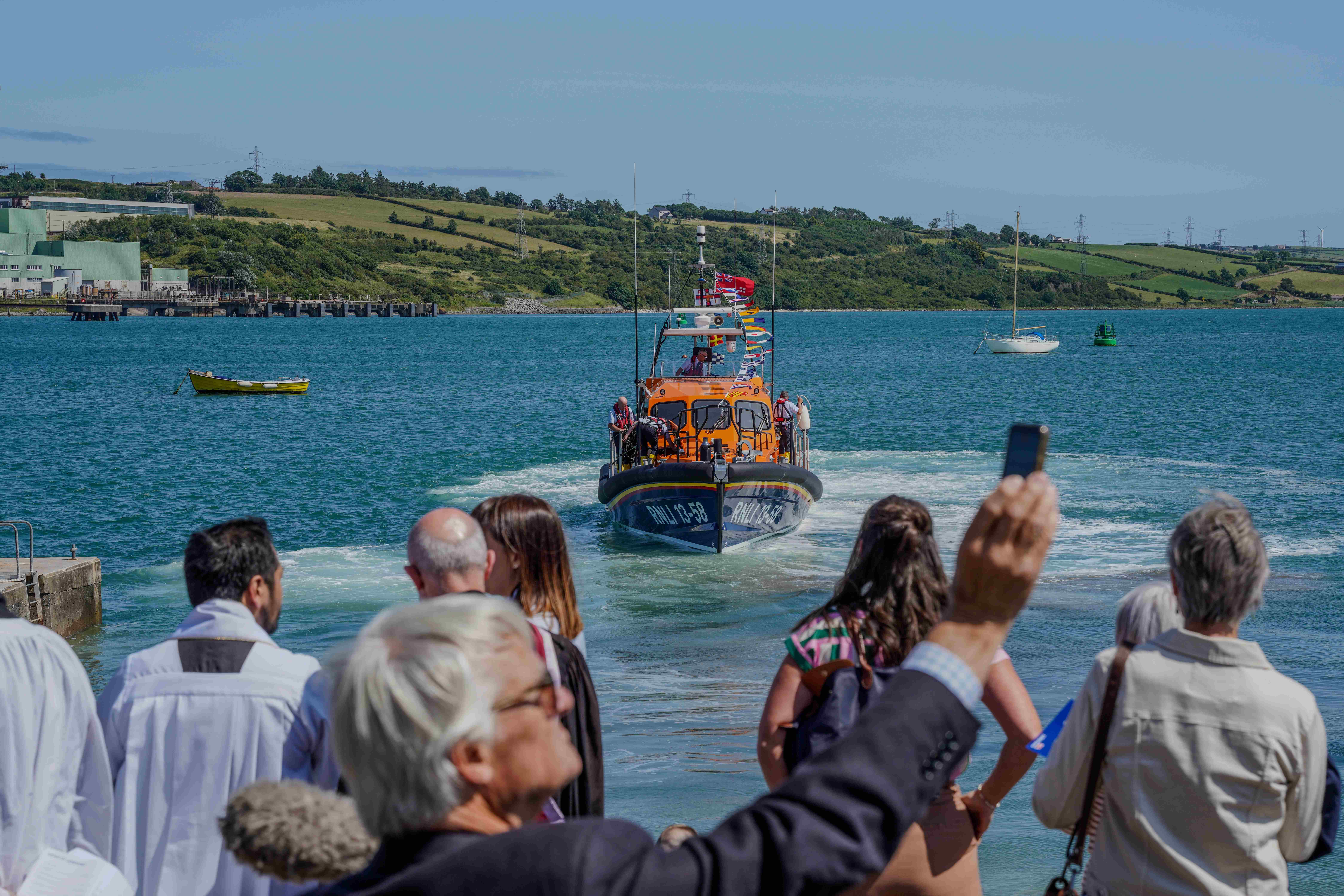 A crowd of onlookers watch the Shannon at sea after the ceremony