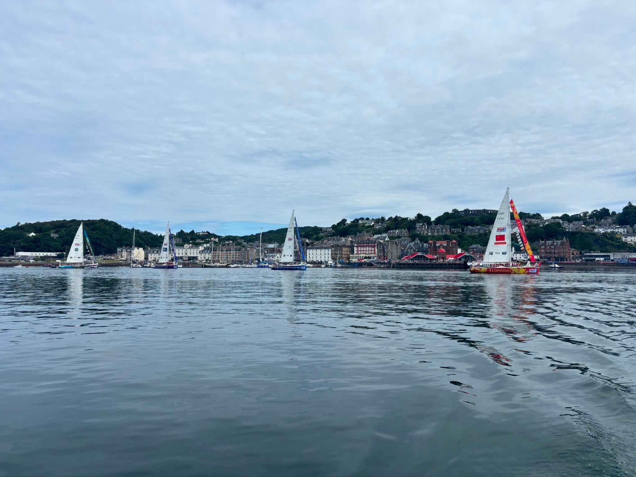 Three of the yachts on a mirror like water with Oban in teh background