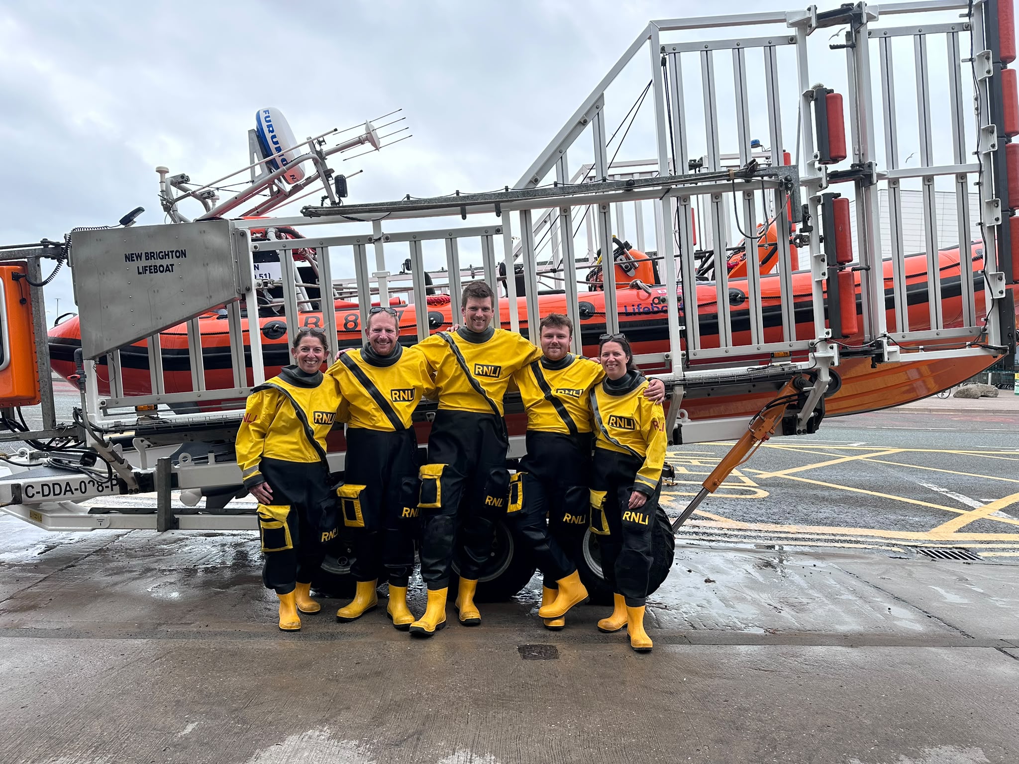 Shows five crew members stood infront of an Atlantic 85 Lifeboat