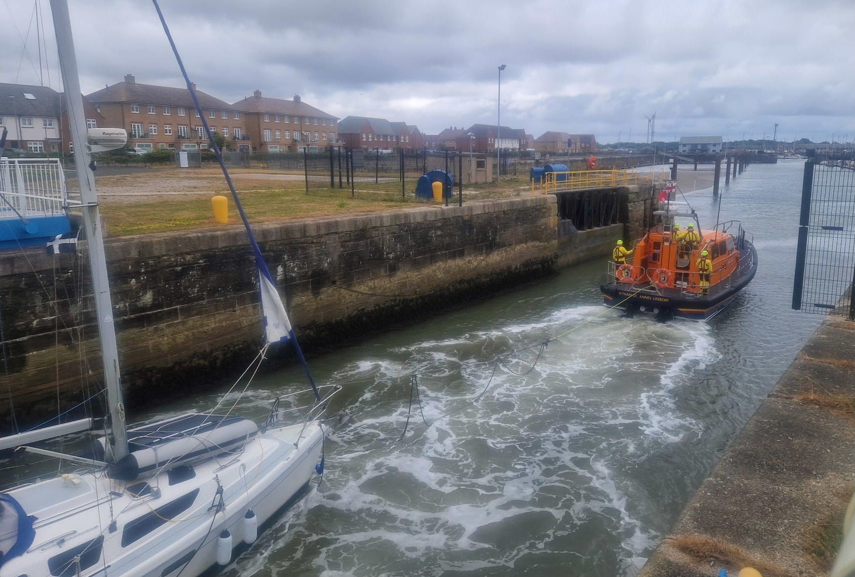 A Lifeboat tows a yacht into a marina